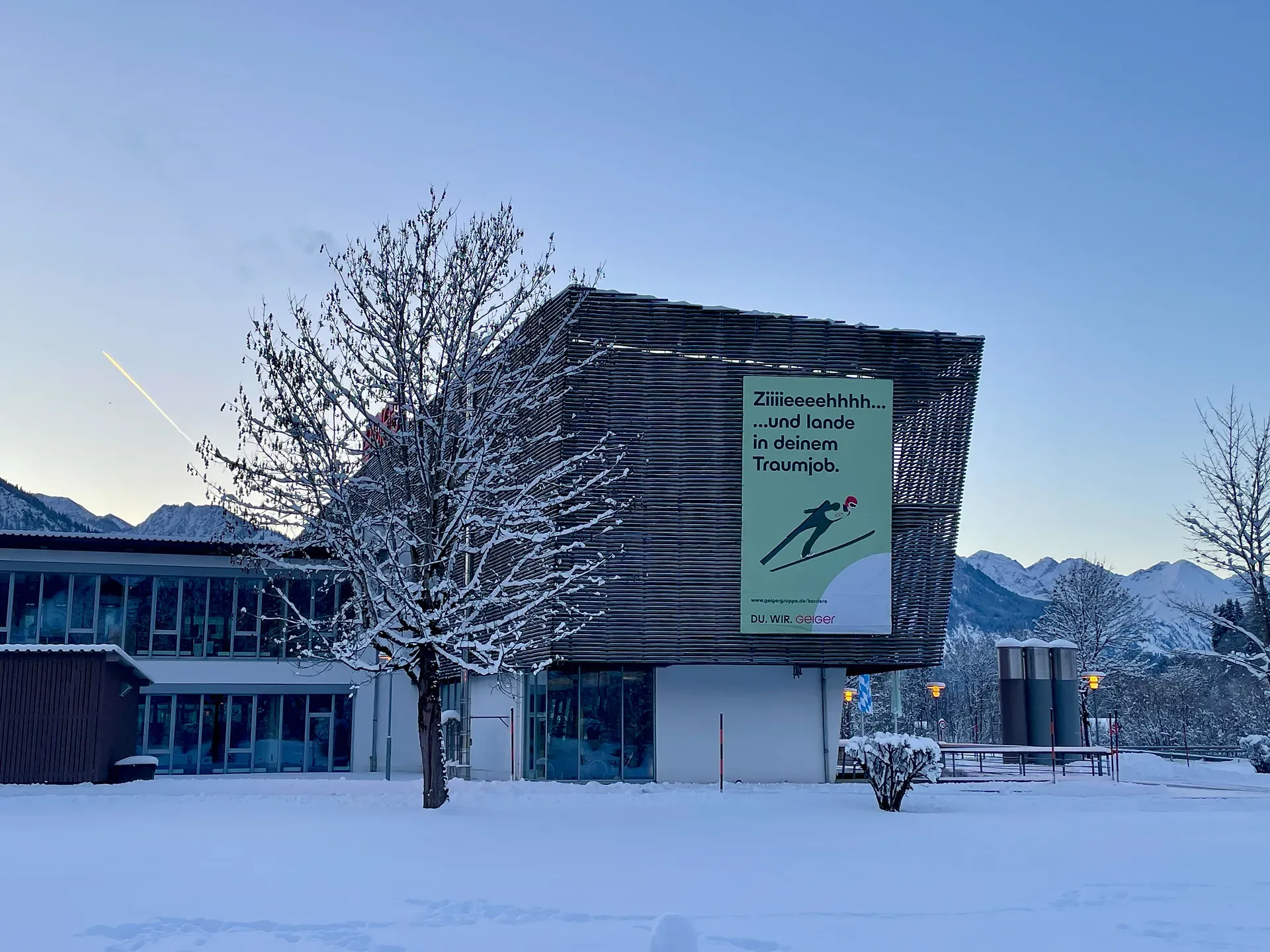 Geiger Standort in Oberstdorf mit einem großen Werbeplakat zur Mitarbeitersuche