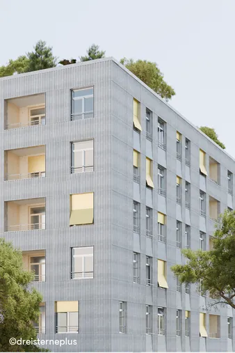 Modernes mehrstöckiges Gebäude mit gelben Sonnenschutzlamellen an den Fenstern und begrünter Dachfläche, umgeben von Bäumen.