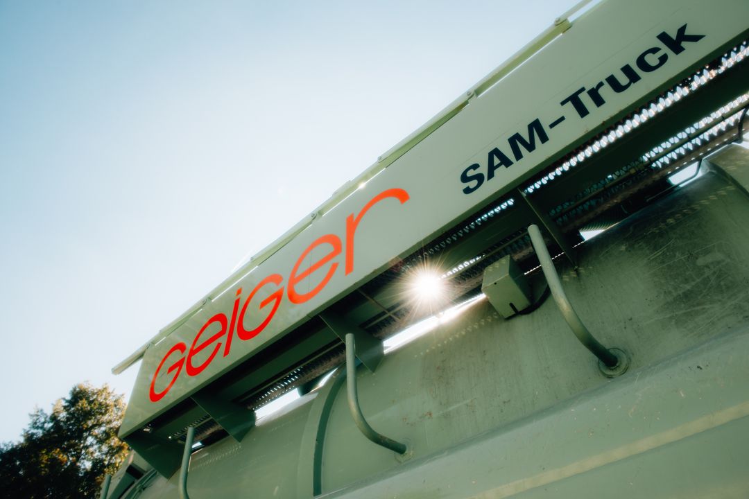 Teil des grünen Geiger SAM-Truck Saugbaggers mit den Firmenlogos.