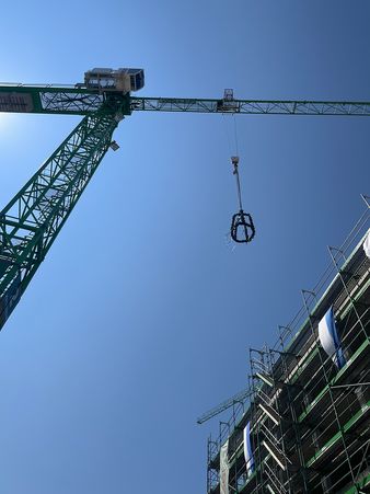 Die Richtkrone wird beim Richtfest von einem Kranen herabgelassen.