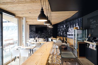 Modernisierter Barbereich der Erdinger Sportalp in Oberstdorf mit stillvoller Einrichtung, gedeckten Tischen und warmen Licht.