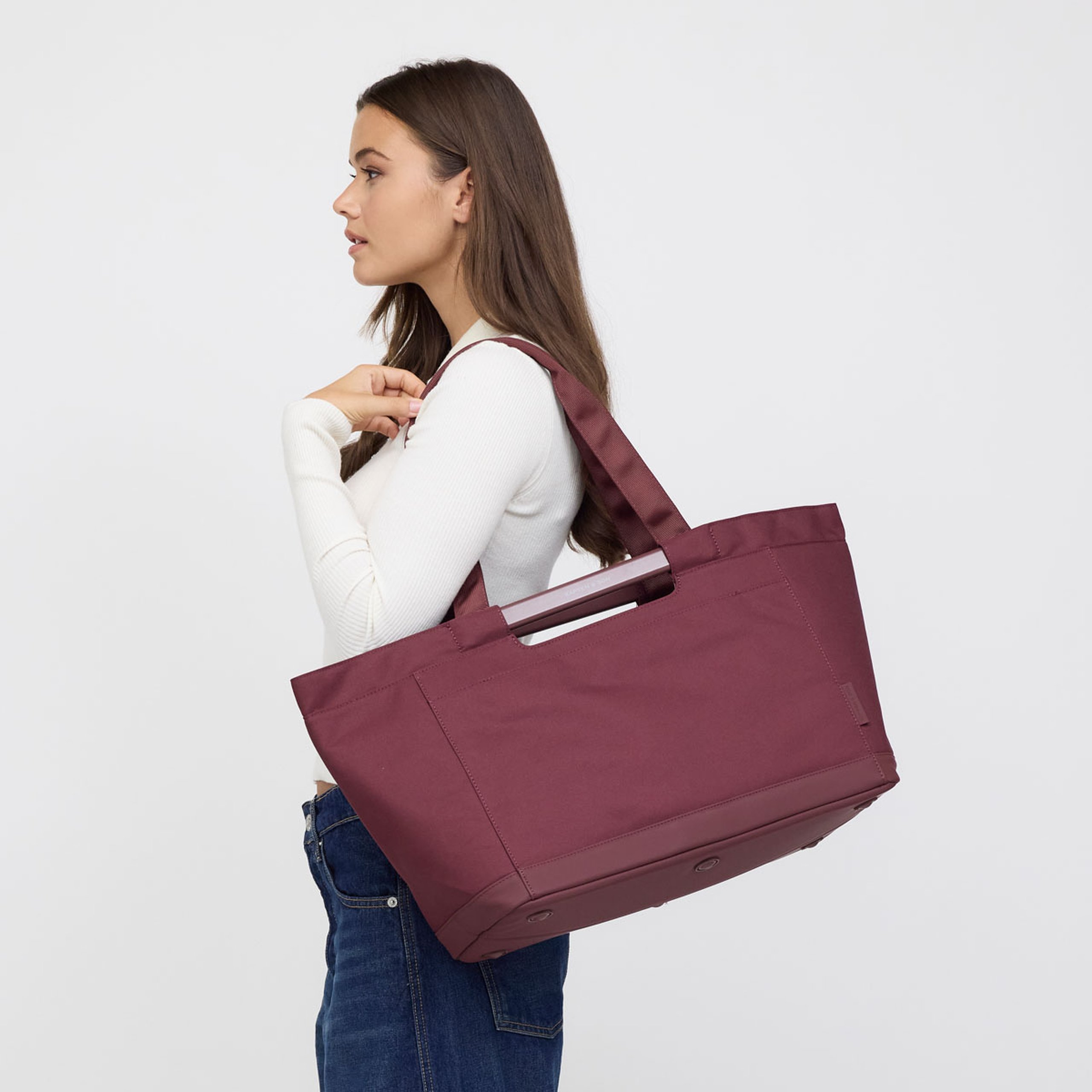 Woman carrying a large shopping basket over her shoulder, shown in side profile.