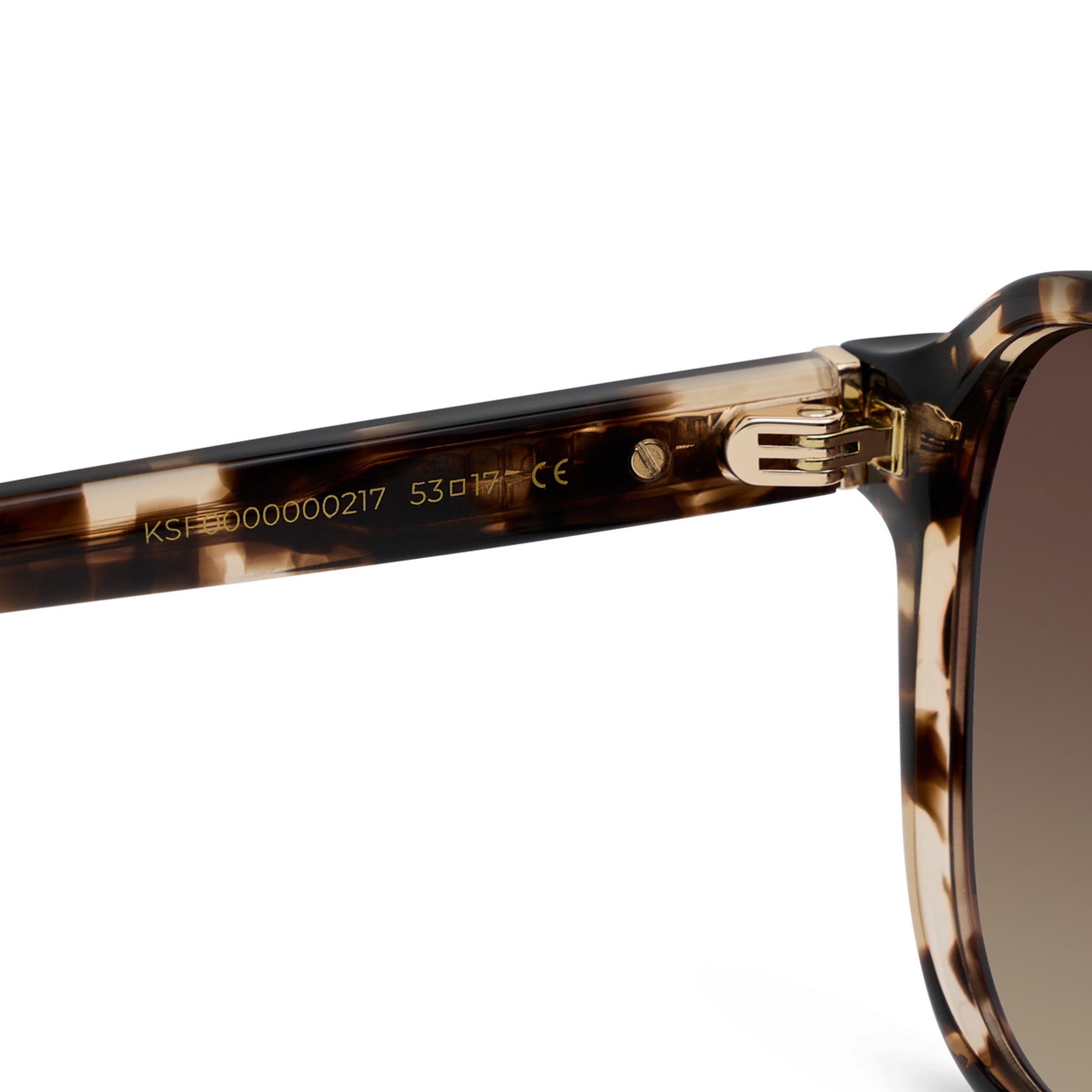 Close-up of tortoiseshell sunglasses showing detailed gold hinge and model number etched on the arm. The design appears modern and stylish.