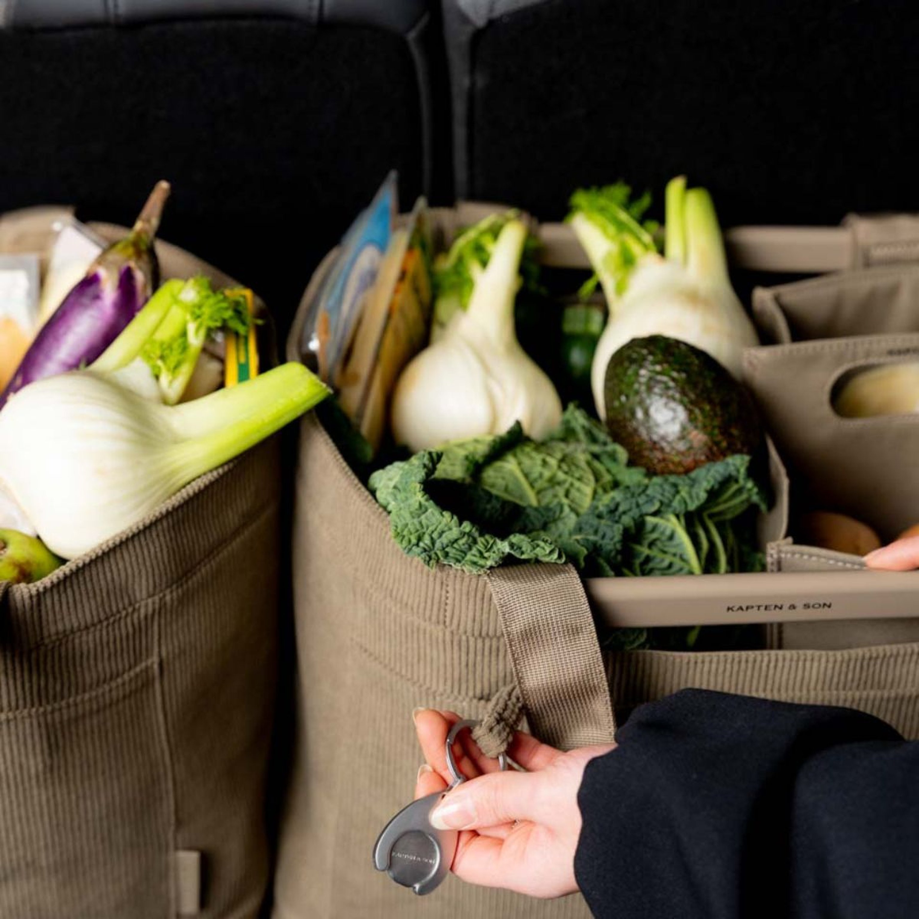Two shopping baskets filled with various items, including bananas, cabbage, and baguettes, neatly placed in the open trunk of a car.