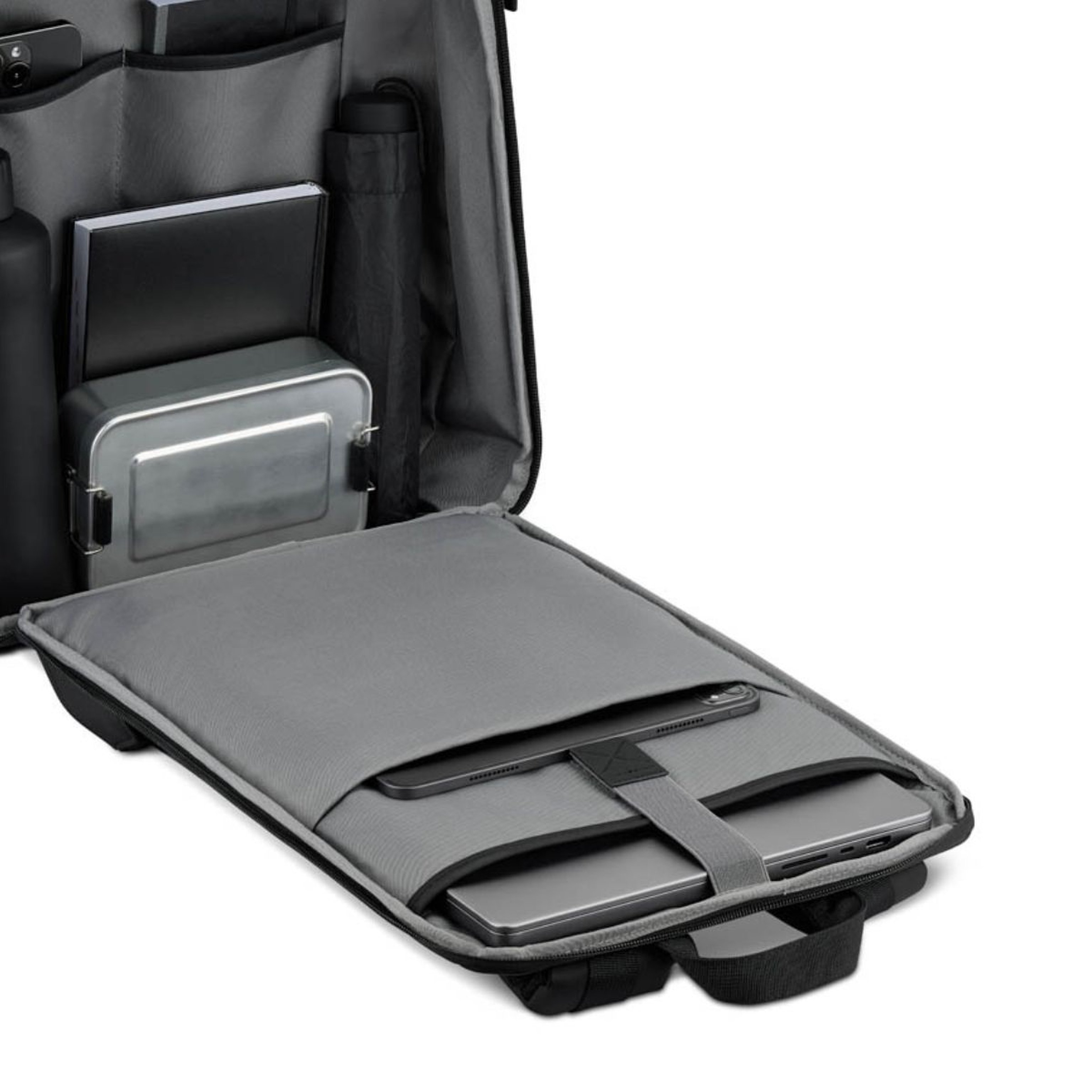 Geöffneter Rucksack mit übersichtlich organisierten Inhalten: Bücher, eine Lunchbox, ein Regenschirm, eine Wasserflasche und ein gepolstertes Laptopfach. Funktional und ordentlich arrangiert.