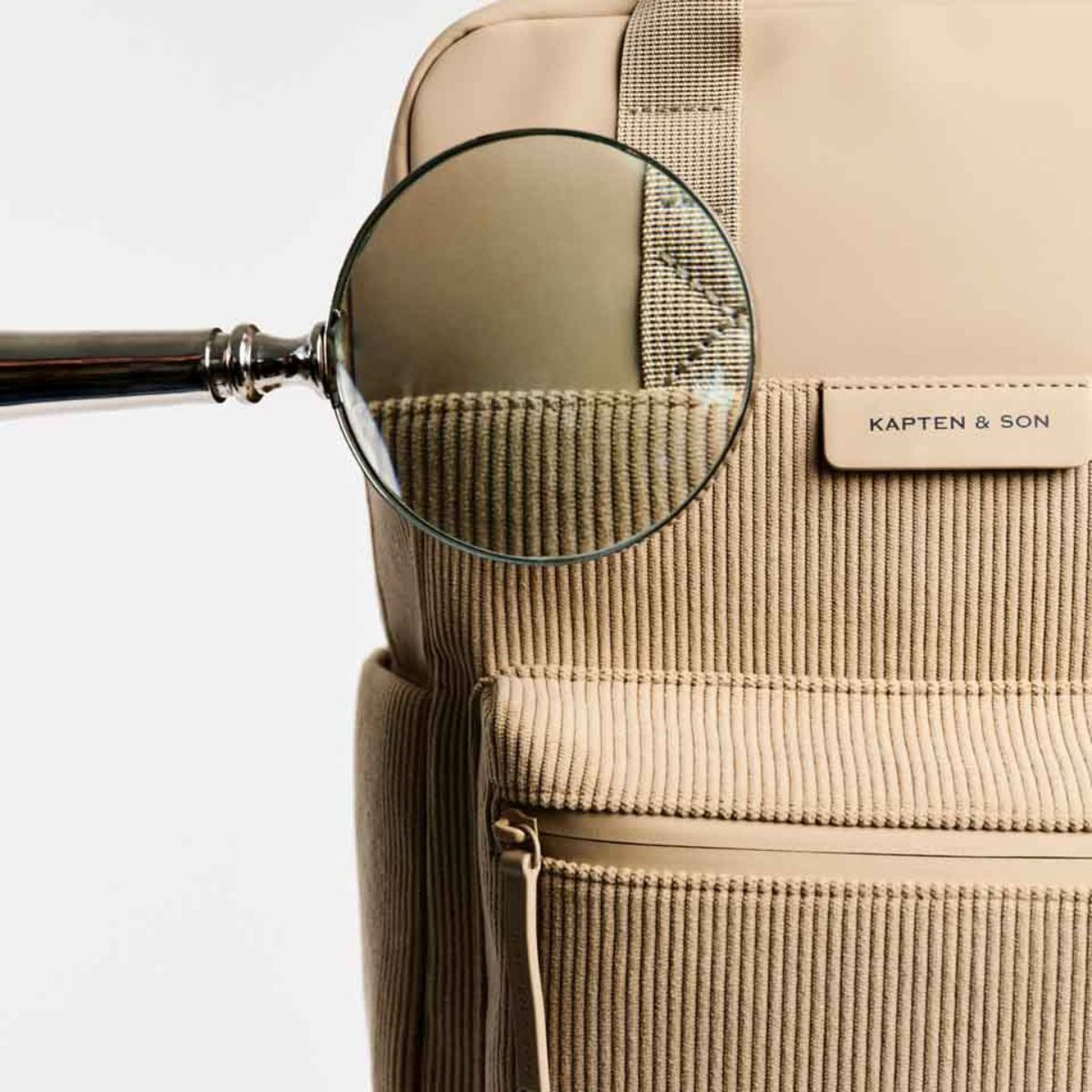 Beige rugzak met een vergrootglas-ontwerp, dat de structuur van het materiaal benadrukt.