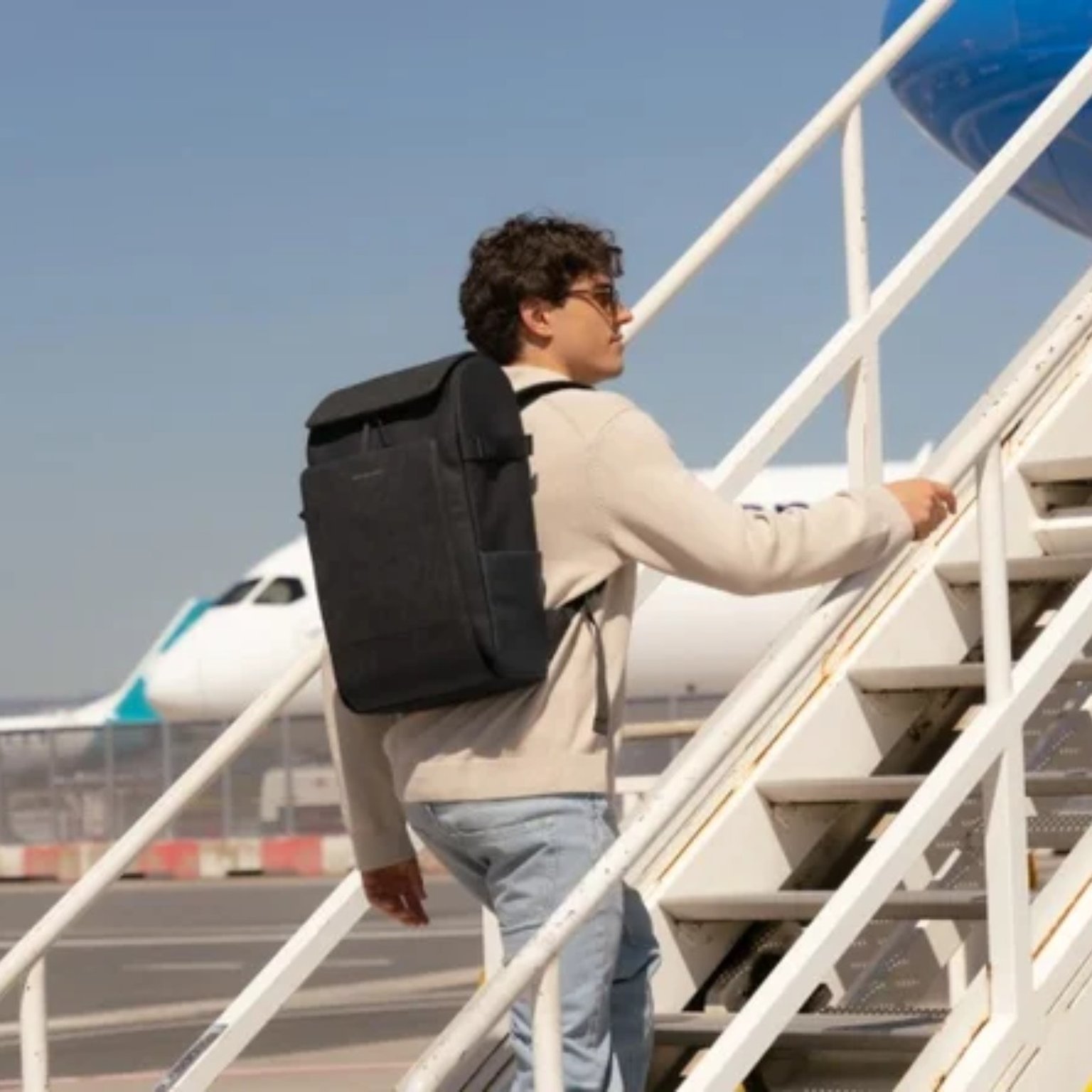 mann läuft treppe zum condor flieger hoch und trägt einen kapten son rucksack