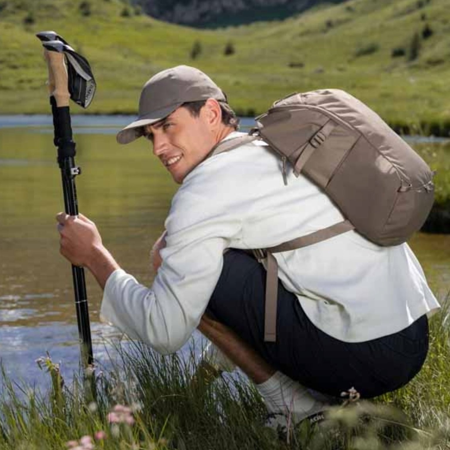 junger mann mit wanderstöcken und kapten and son wanderrucksack rastet an einem fluss