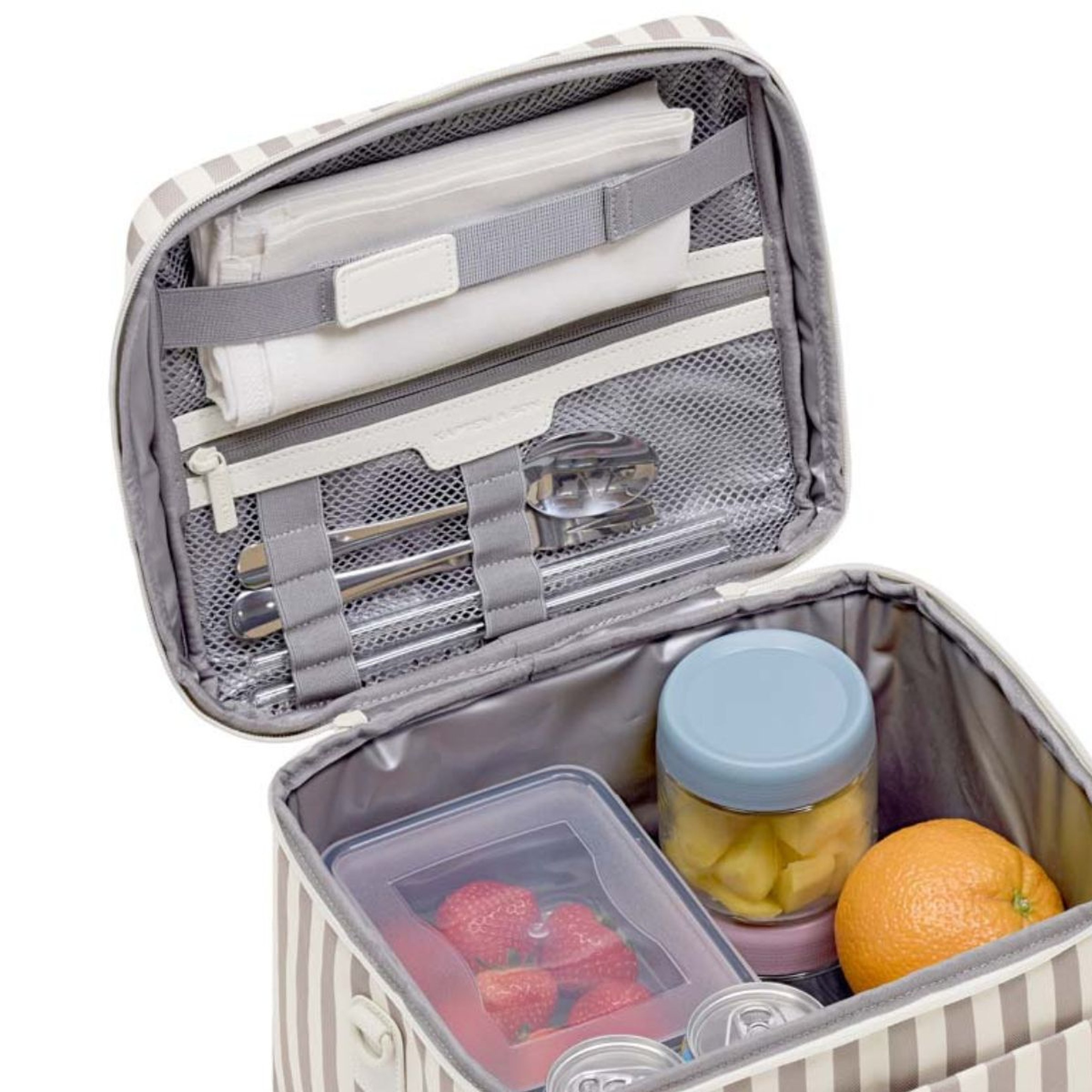 Striped lunchbox open to reveal silverware, napkin, strawberries in a container, sliced fruit in a jar, and an orange, all neatly organized.