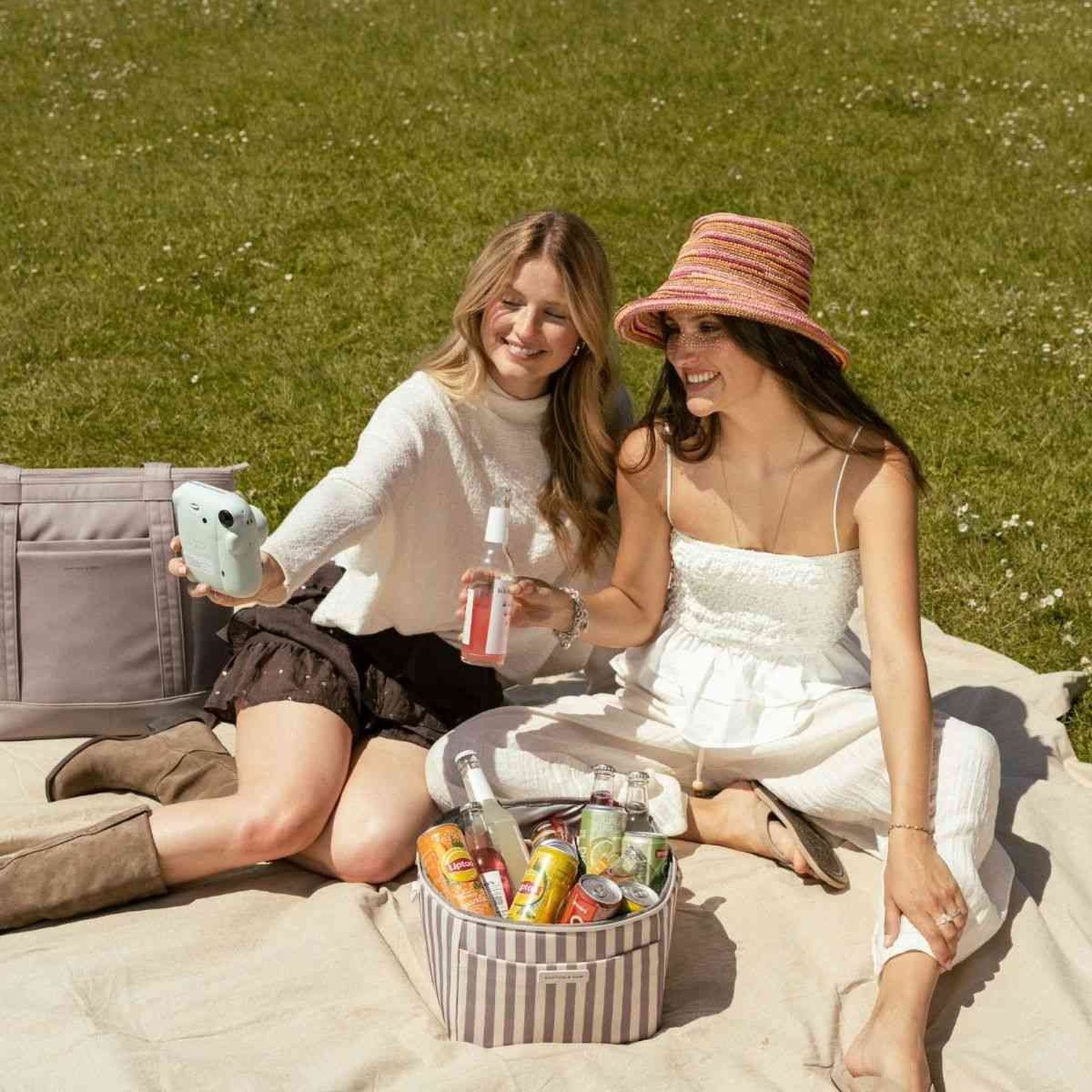 zwei frauen sitzen auf einer picknickdecke im park