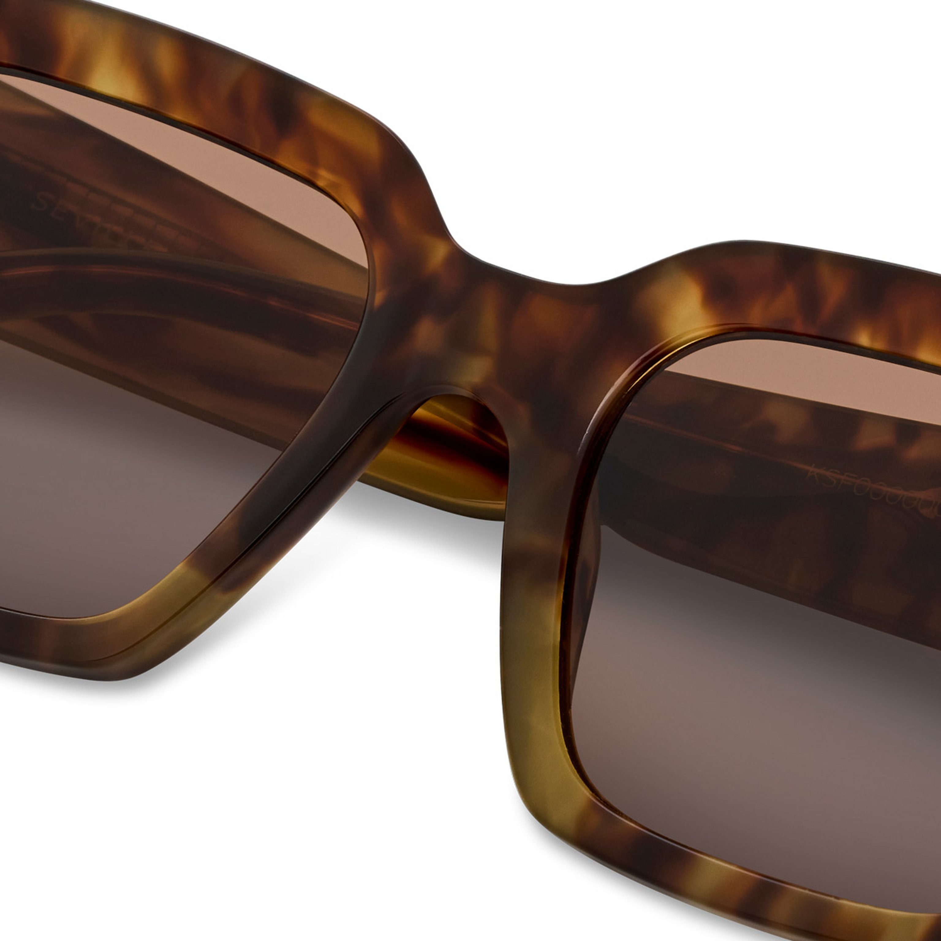 Close-up of tortoiseshell sunglasses with brown gradient lenses. The stylish frame features a classic design with a modern, sophisticated feel.