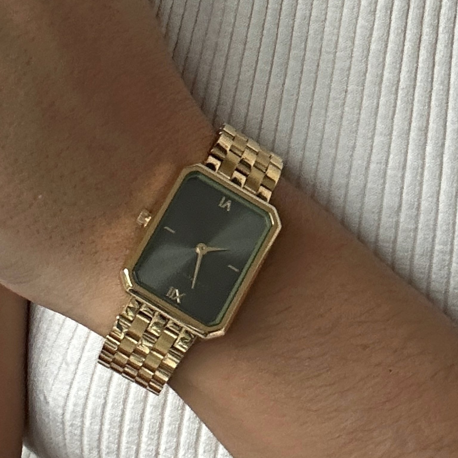 frau trägt eine schlichte goldene armbanduhr am handgelenk