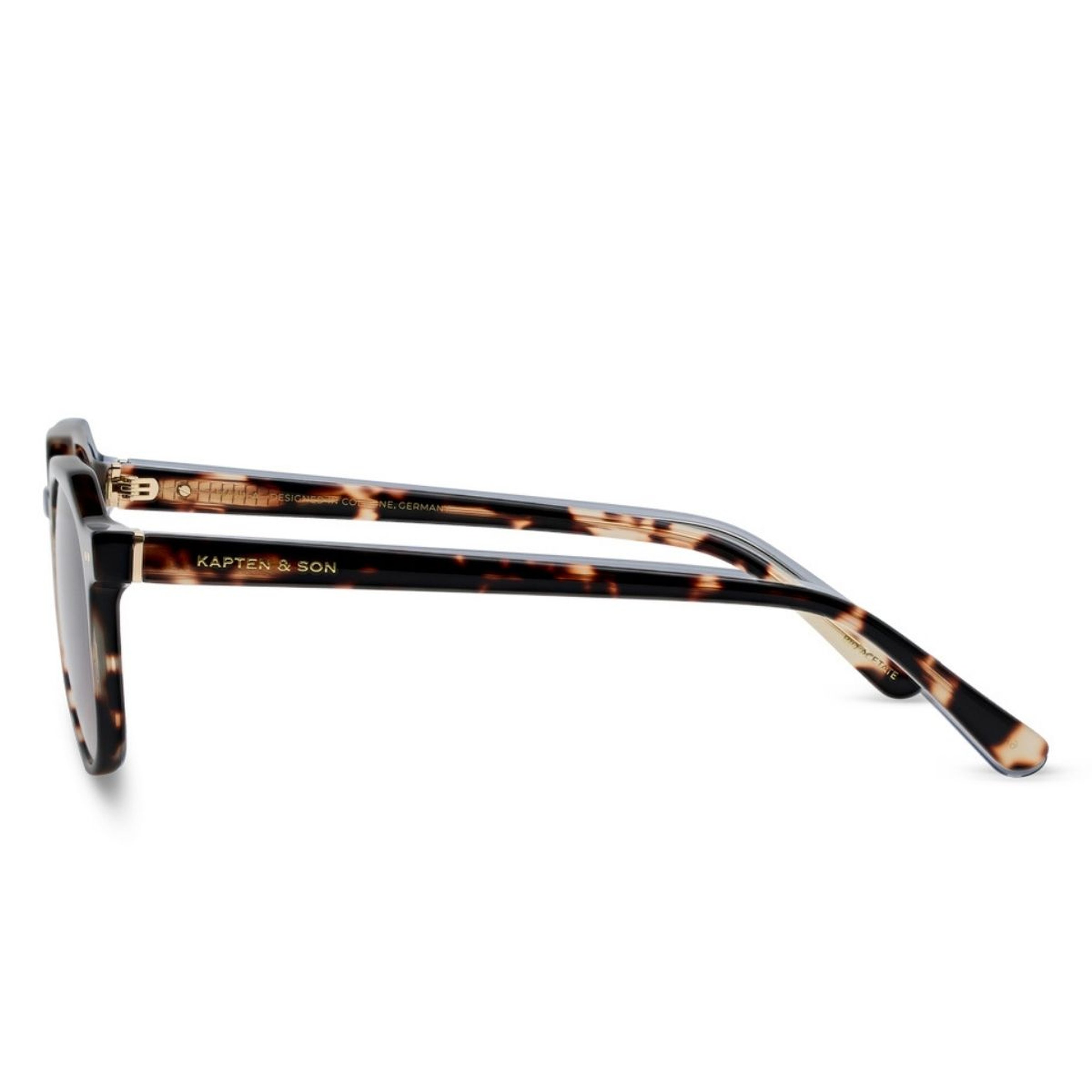 Side view of tortoiseshell sunglasses with "Kapten & Son" logo on the arms. The frame features a sleek design, conveying a modern, stylish tone.