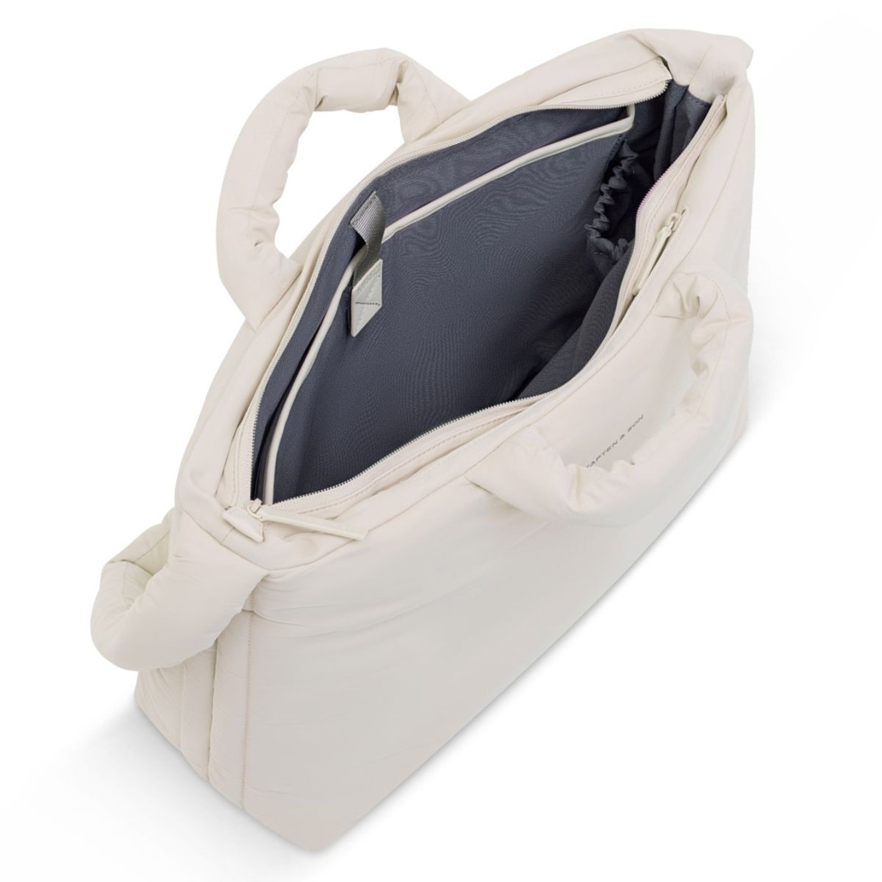 Bovenaanzicht van een stijlvolle, crèmekleurige tote bag met gedeeltelijk open rits, die een ruim, donkergrijs interieur met vakken onthult. De gewatteerde handvatten suggereren comfort en functionaliteit.