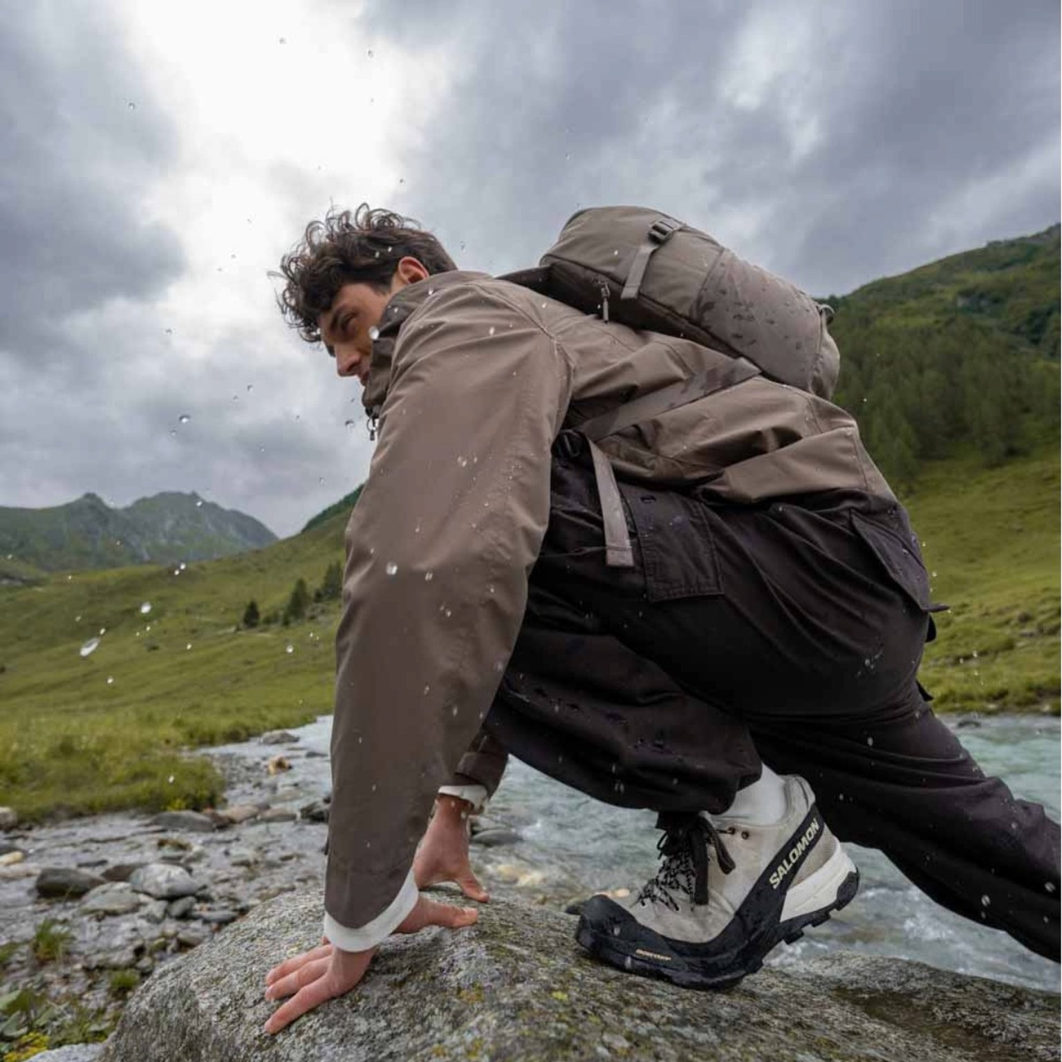 junger mann mit regenjacke von kapten and son wandert im gebirge