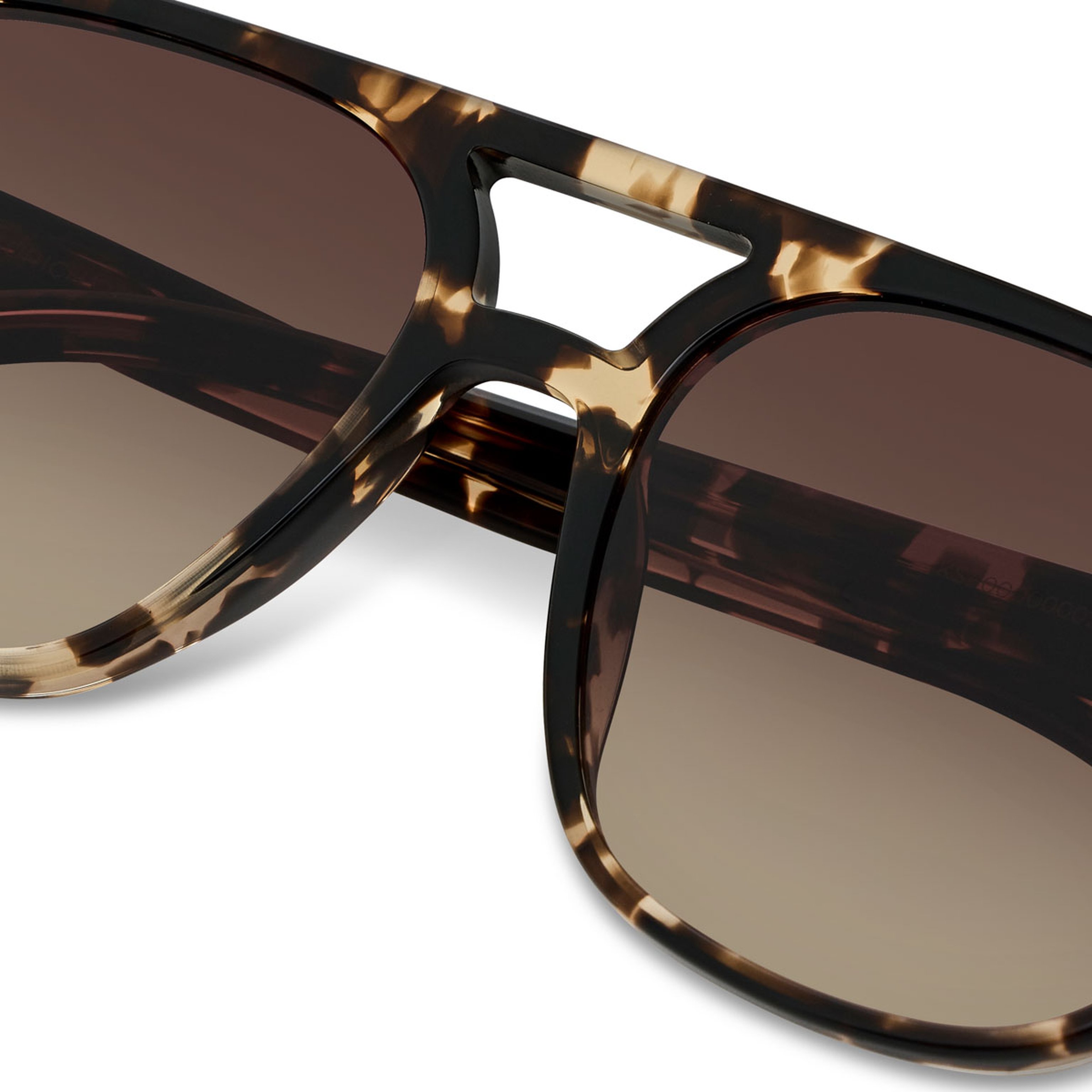 Close-up of tortoiseshell sunglasses with brown gradient lenses. The stylish frame features a classic design with a modern, sophisticated feel.