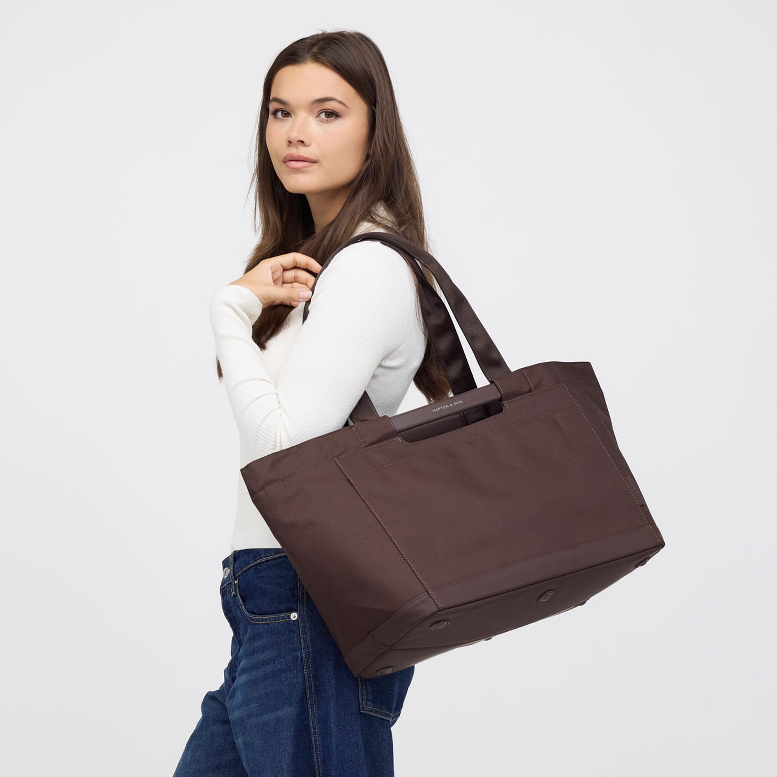 Woman carrying a large shopping basket over her shoulder, shown in side profile.