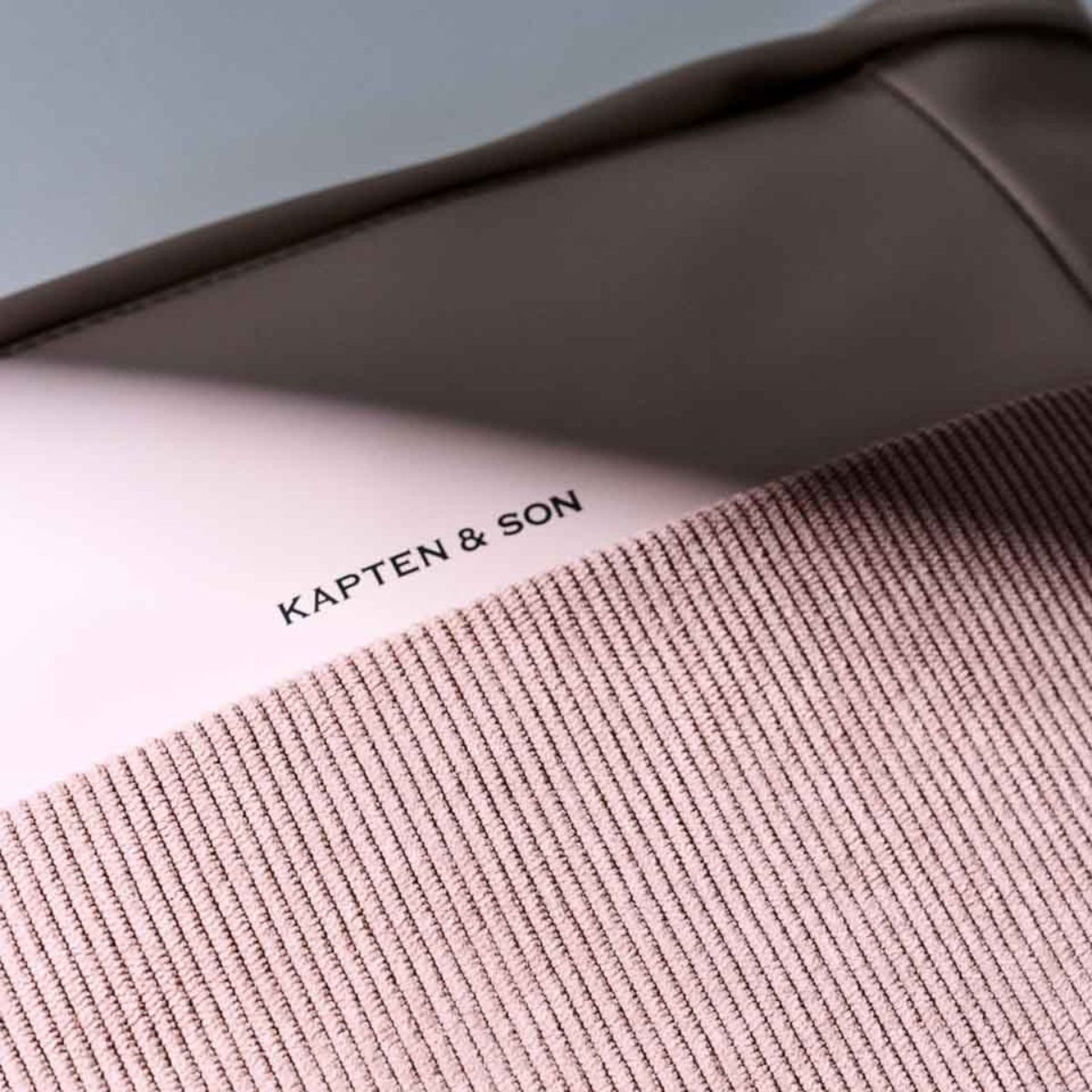 A pink backpack featuring the name "Kapten and Son" prominently displayed on its surface.