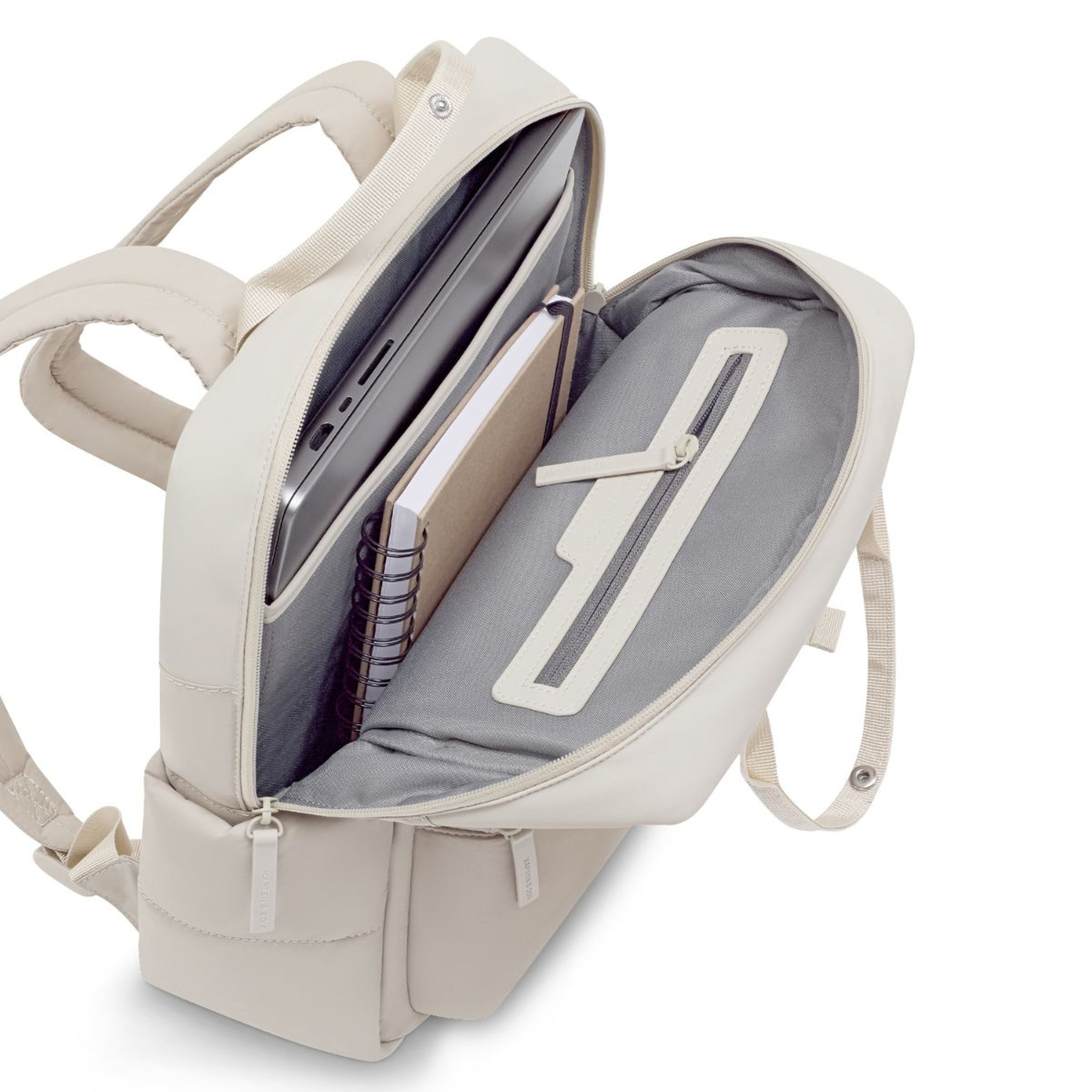 Open witte rugzak met een grijs interieur, met netjes georganiseerde notitieboeken en mappen binnenin, wat een gevoel van voorbereiding en orde uitstraalt.