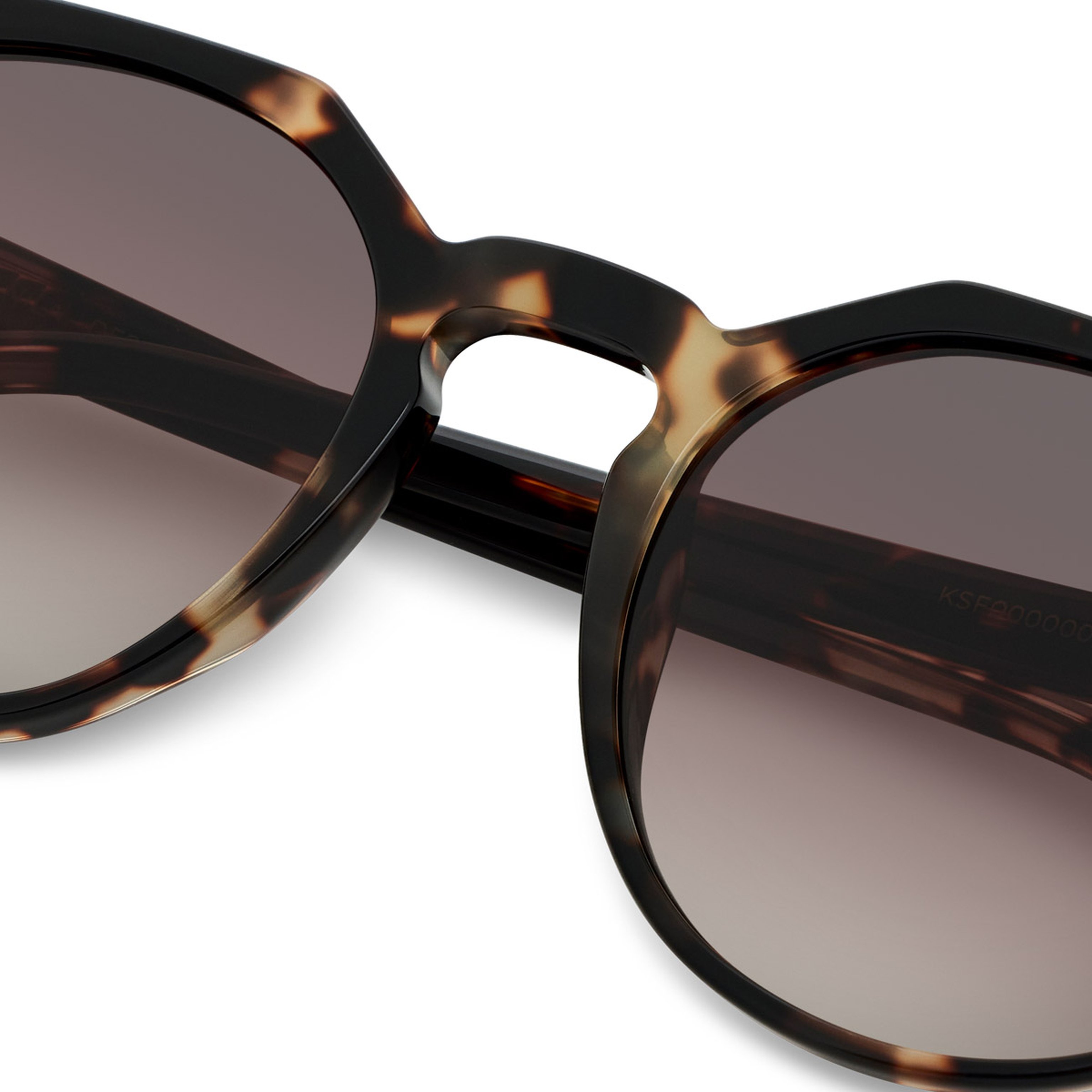 Close-up of tortoiseshell sunglasses with brown gradient lenses. The stylish frame features a classic design with a modern, sophisticated feel.
