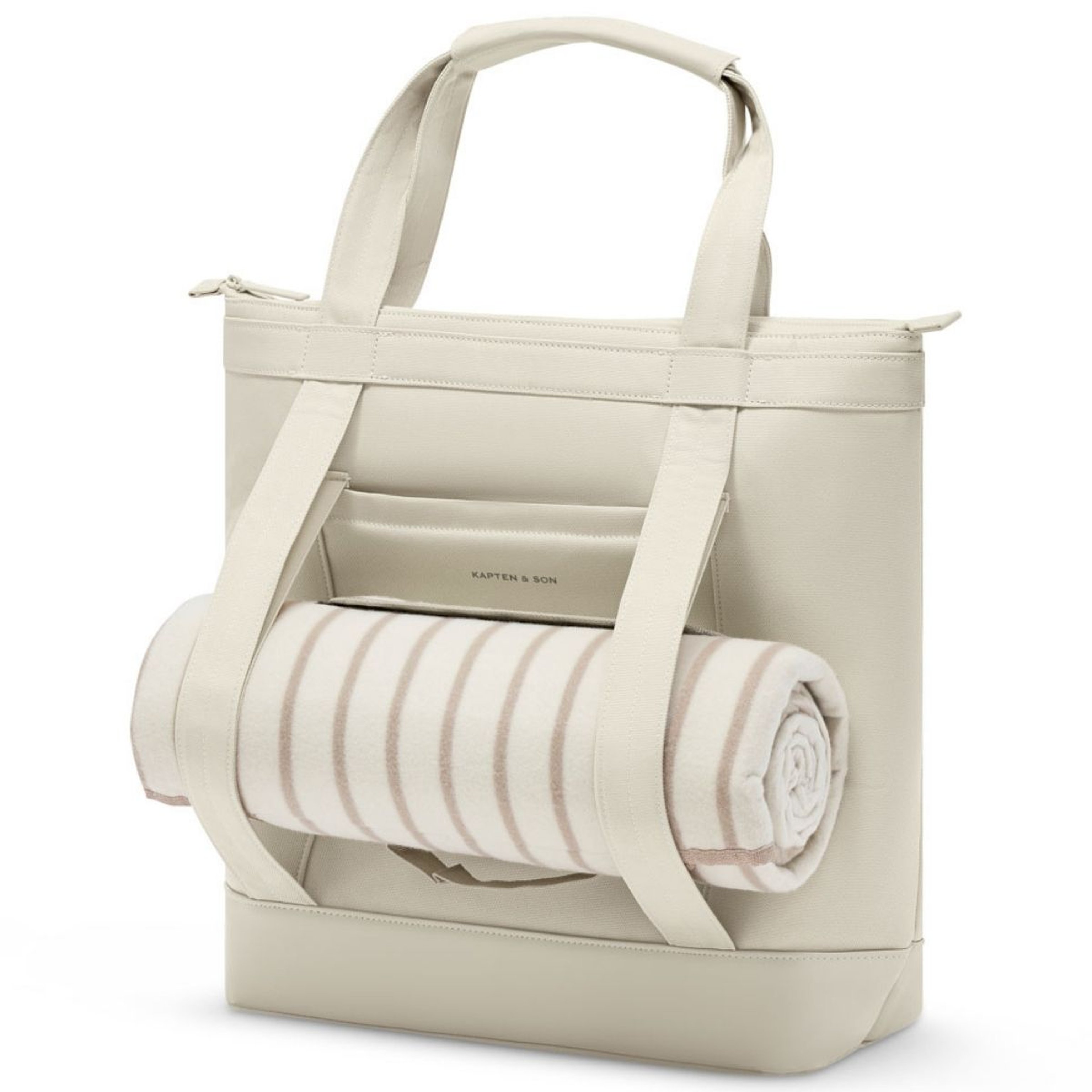 Cream-colored tote bag with two handles and a front pocket. A rolled-up beige and white striped blanket is secured under straps, creating a cozy feel.