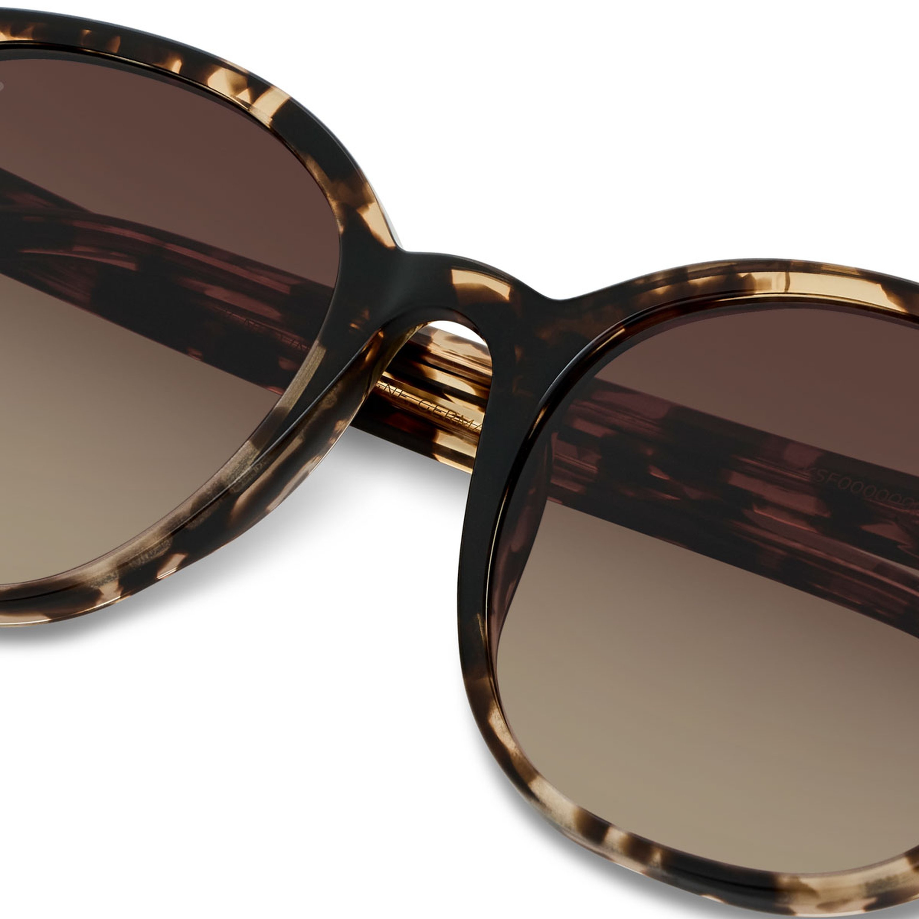 Close-up of tortoiseshell sunglasses with brown gradient lenses. The stylish frame features a classic design with a modern, sophisticated feel.