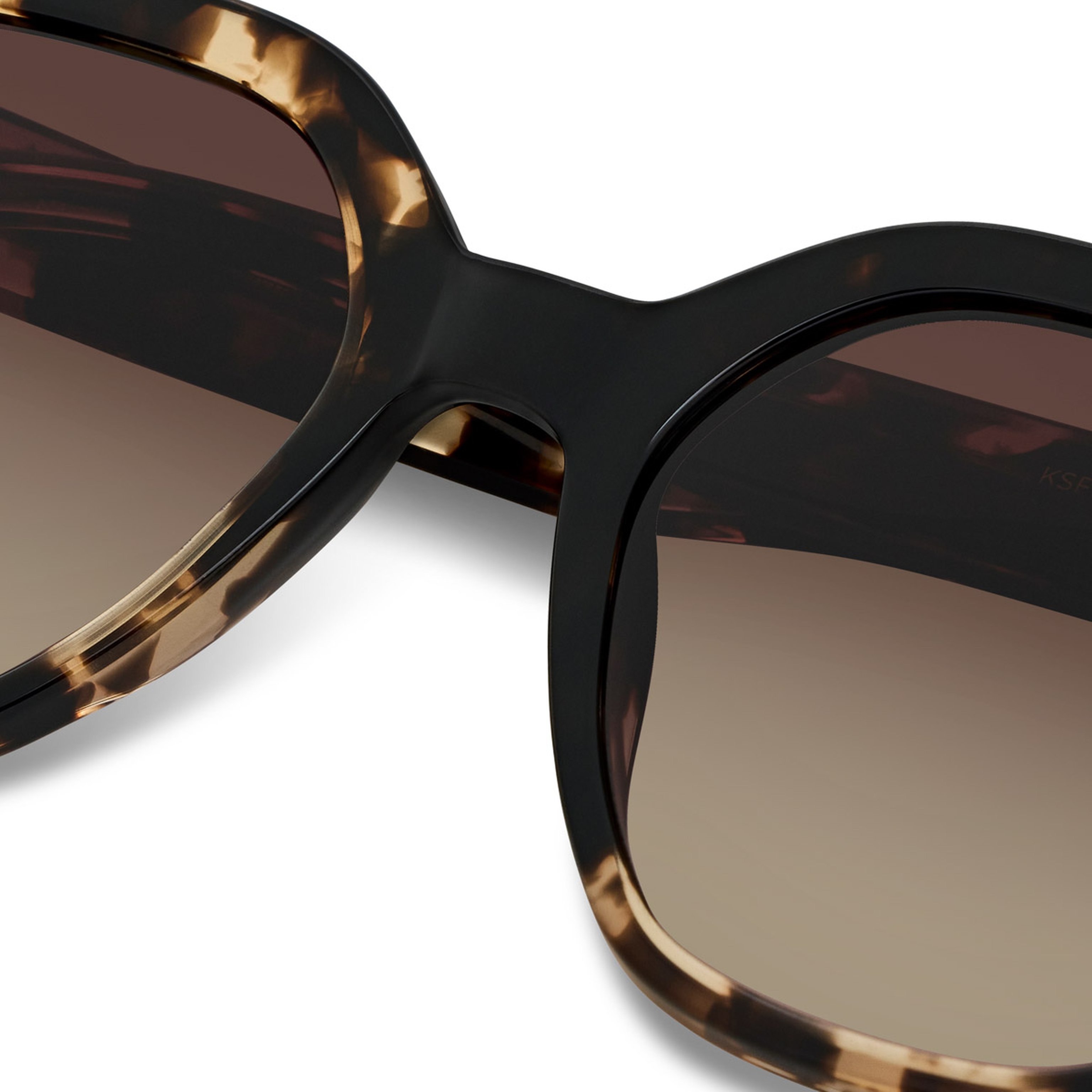Close-up of tortoiseshell sunglasses with brown gradient lenses. The stylish frame features a classic design with a modern, sophisticated feel.