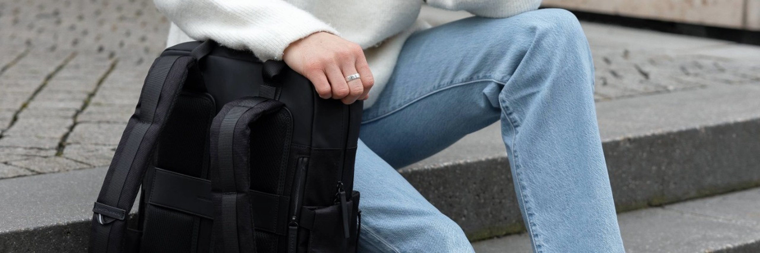 junger mann ruht seinen arm auf einem kapten & son wickelrucksack für männer aus