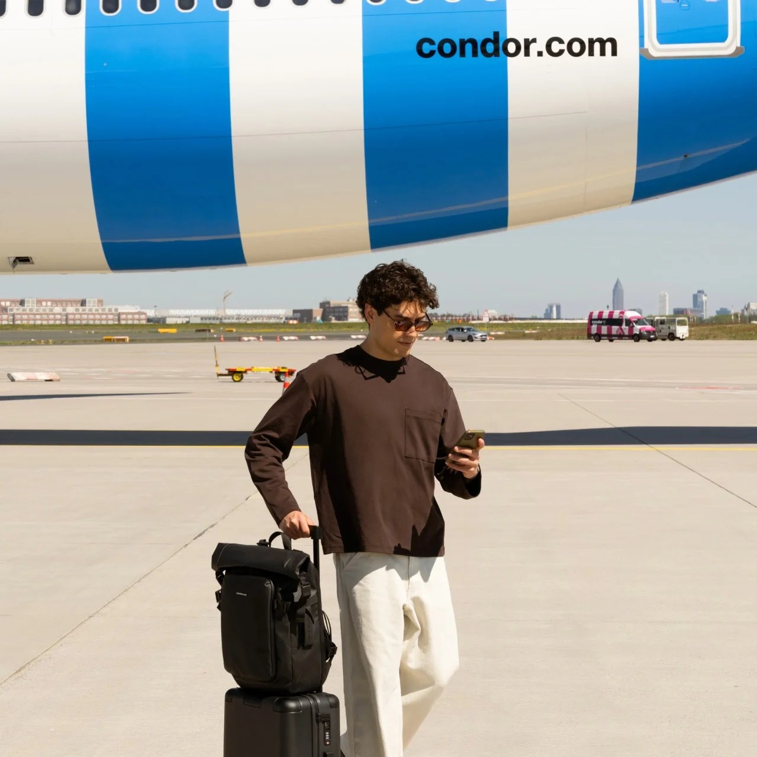 junger mann steht mit kapten son koffer und rucksack vor condor flieger