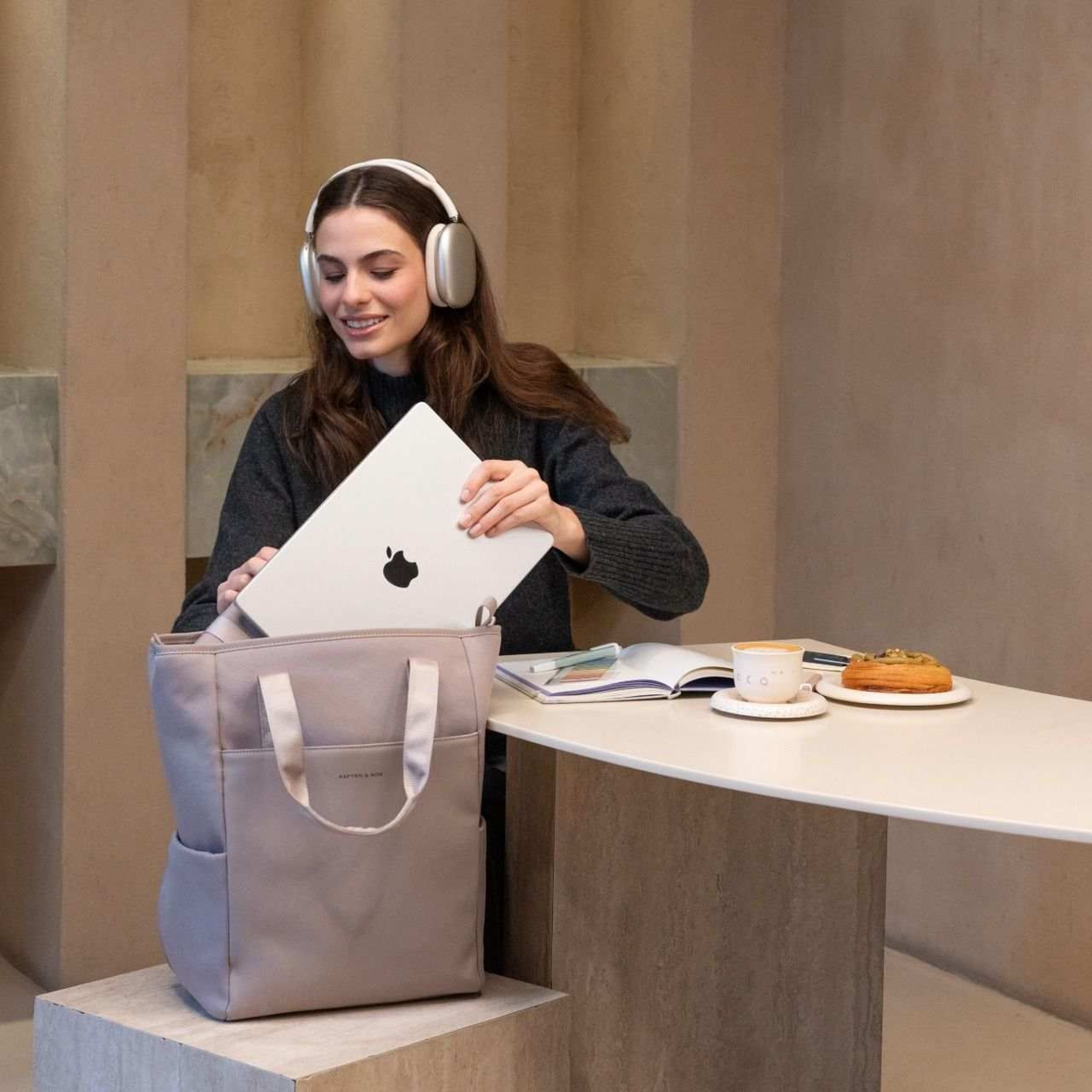frau sitzt im cafe und packt ihren laptop ein