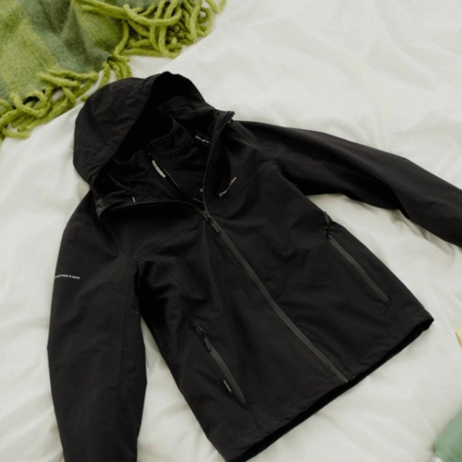 schwarze jacke leigt auf dem bett