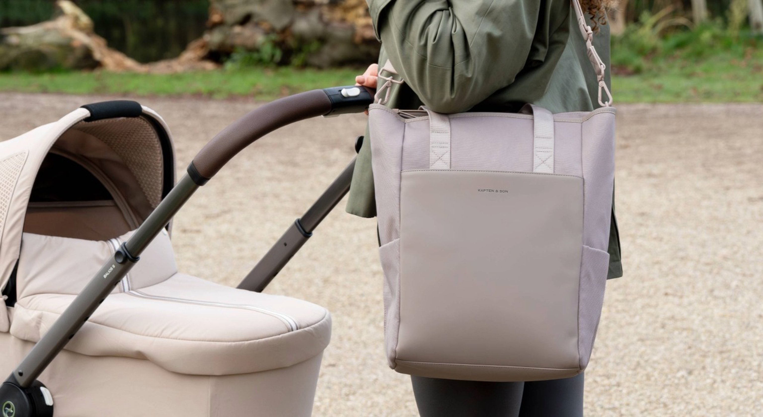 frau trägt rosa wickeltasche von kapten & son und schiebt kinderwagen