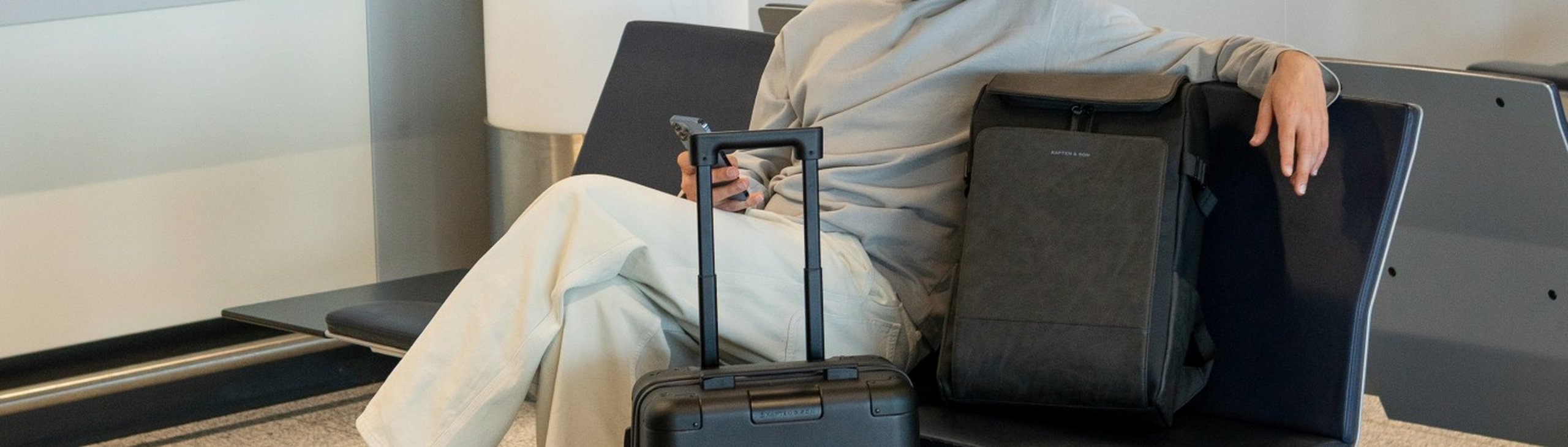 mann sitzt am gate mit handgepäckrucksack von kapten & son 