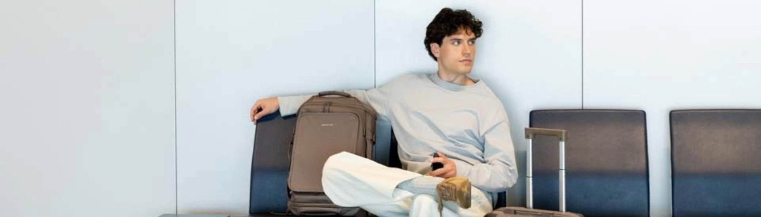 mann sitzt am flughafen mit braunem kapten and son rucksack und wartet aufs boarding.