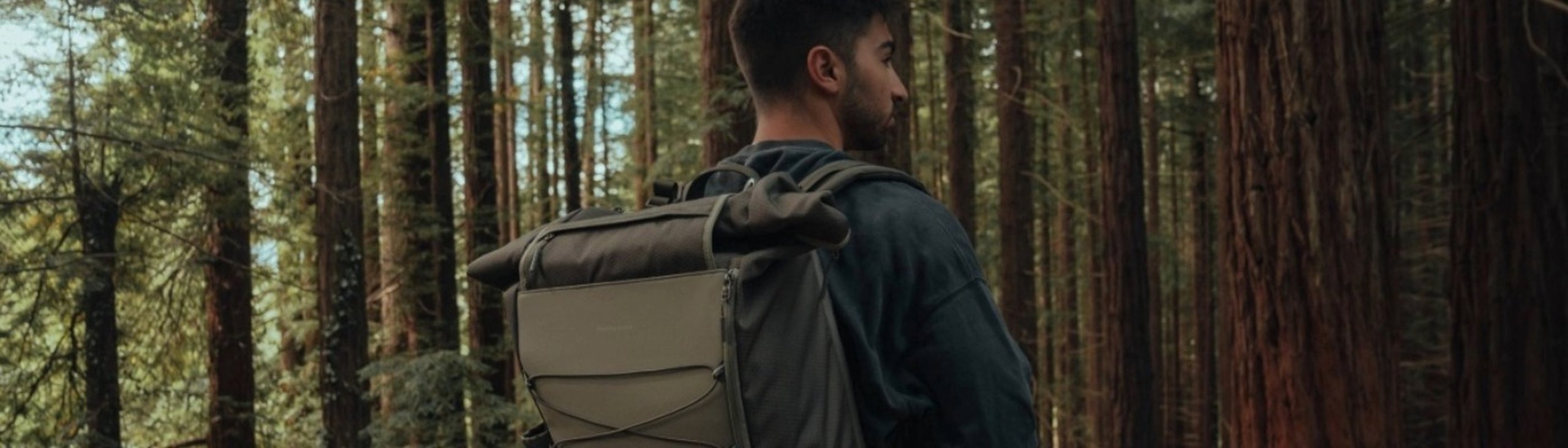 mann mit einem grünen kapten and son rucksack wandert im wald