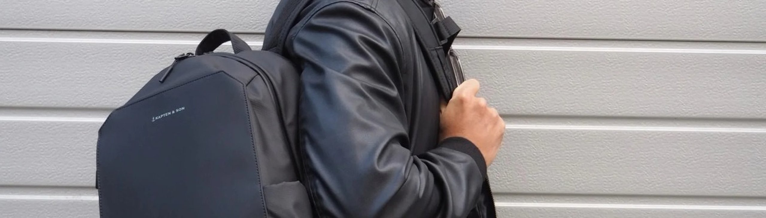 junger mann in lederjacke trägt schwarzen handgepäck rucksack für easyjet flug