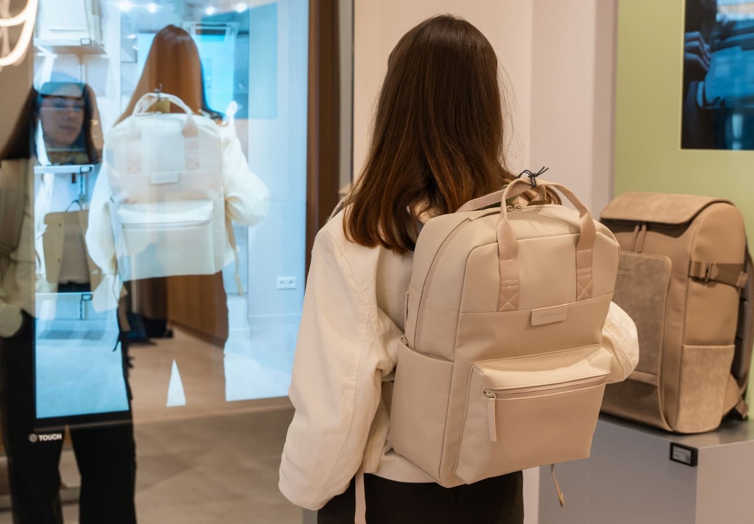 Innenansicht des Kapten & Son Experience Stores – Wandregal mit Taschen, Rucksäcken und Accessoires, Regale mit Reisegepäck und Reisetaschen sowie eine Glasvitrine mit Uhren und Schmuck