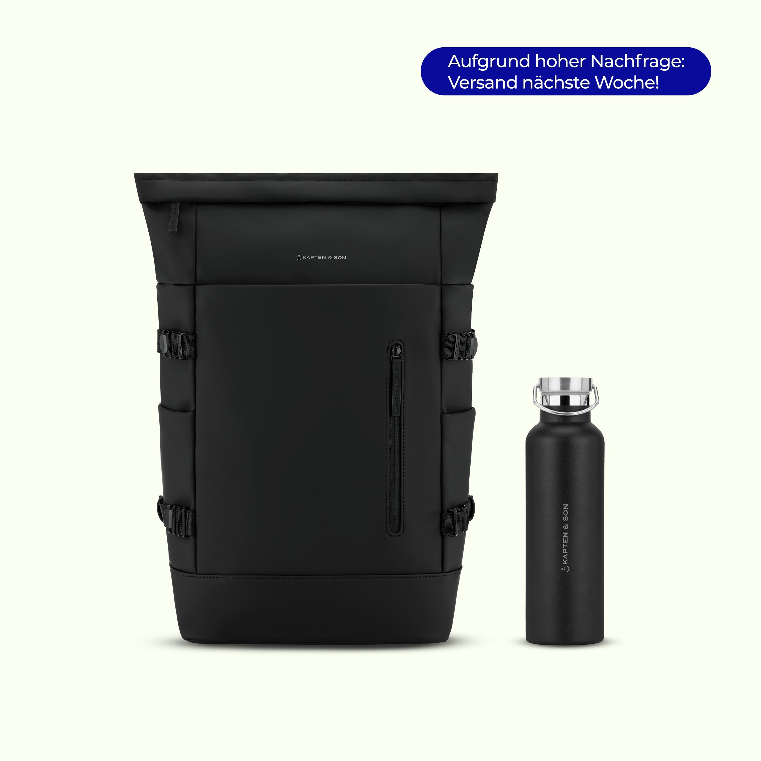 Schwarzer Kapten & Son Helsinki Roll-Top-Rucksack mit seitlichen Schnallen und einem vorderen Reißverschlussfach, neben einer passenden schwarzen Kapten & Son Edelstahl-Trinkflasche mit Silberdeckel auf hellem Hintergrund. Ein blauer Badge zeigt: „Aufgrund hoher Nachfrage: Versand nächste Woche!"