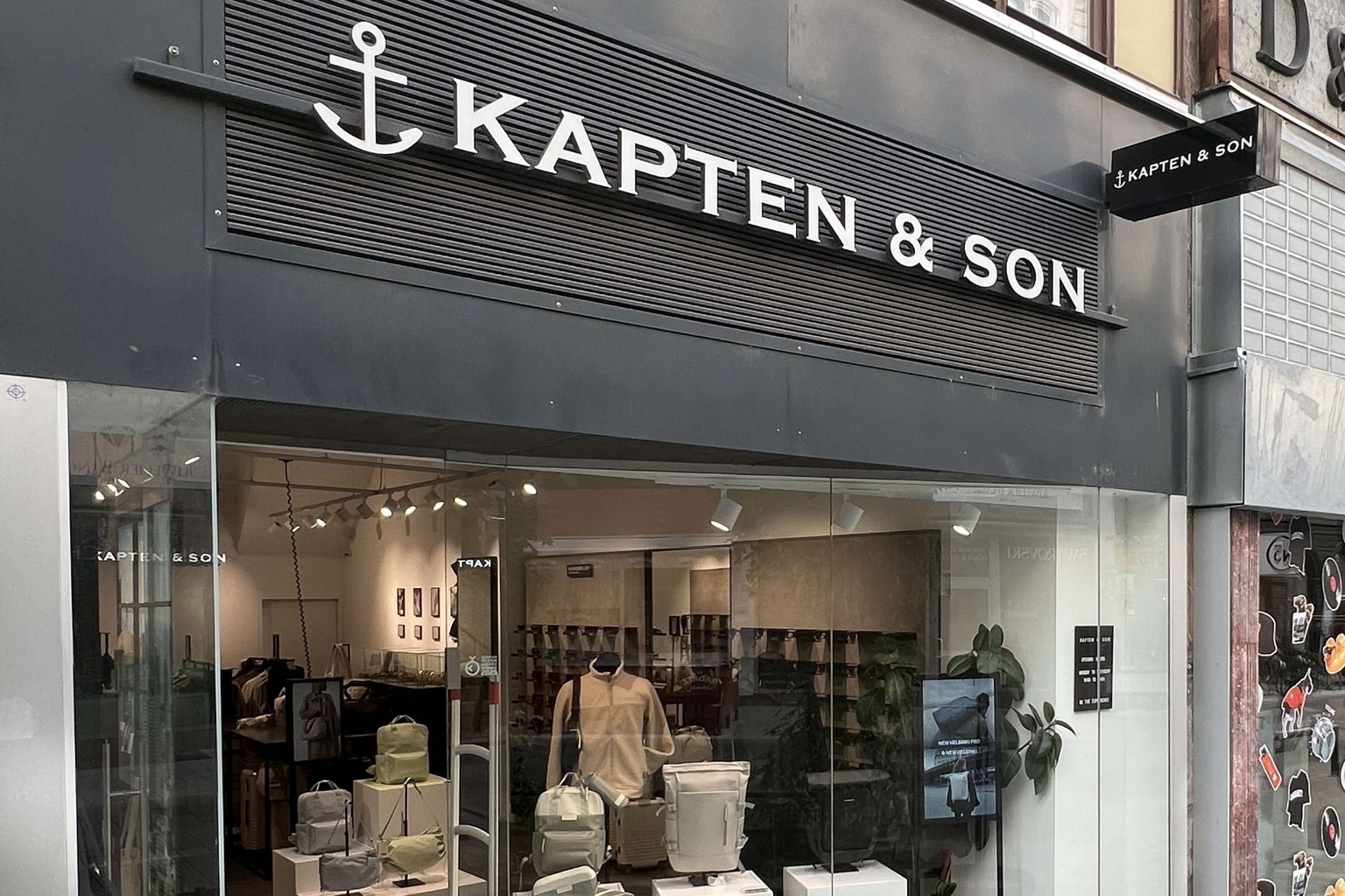 Außenansicht eines Kapten & Son Stores mit großem Schaufenster und Blick ins Ladeninnere