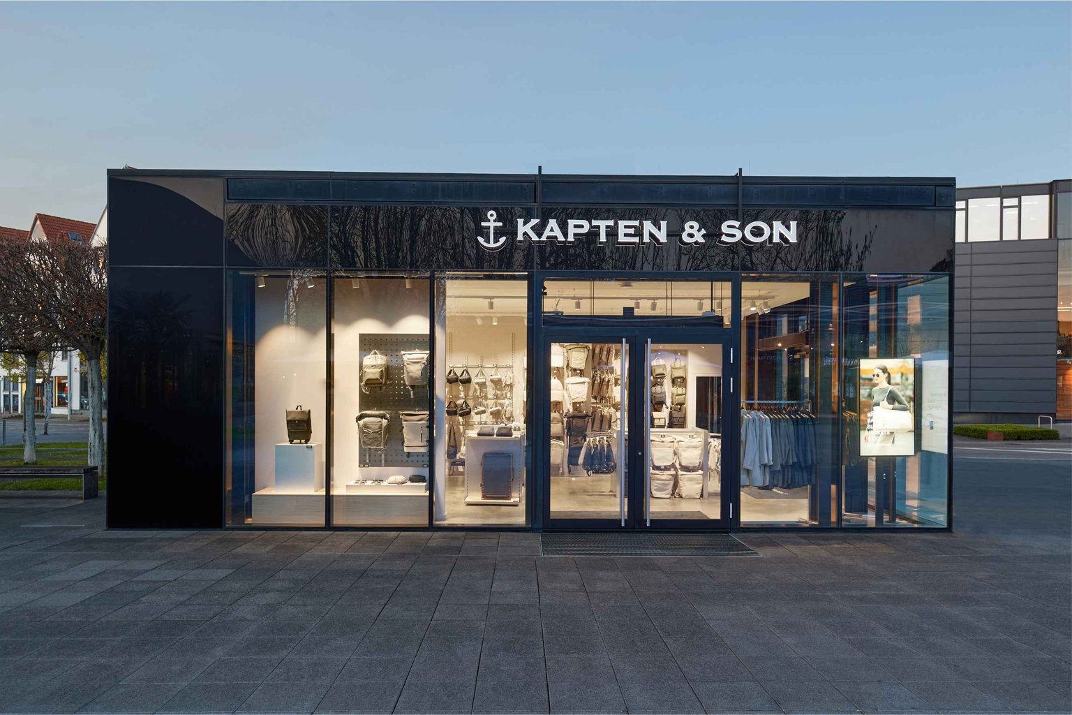 Außenansicht eines Kapten & Son Stores mit großem Schaufenster und Blick ins Ladeninnere