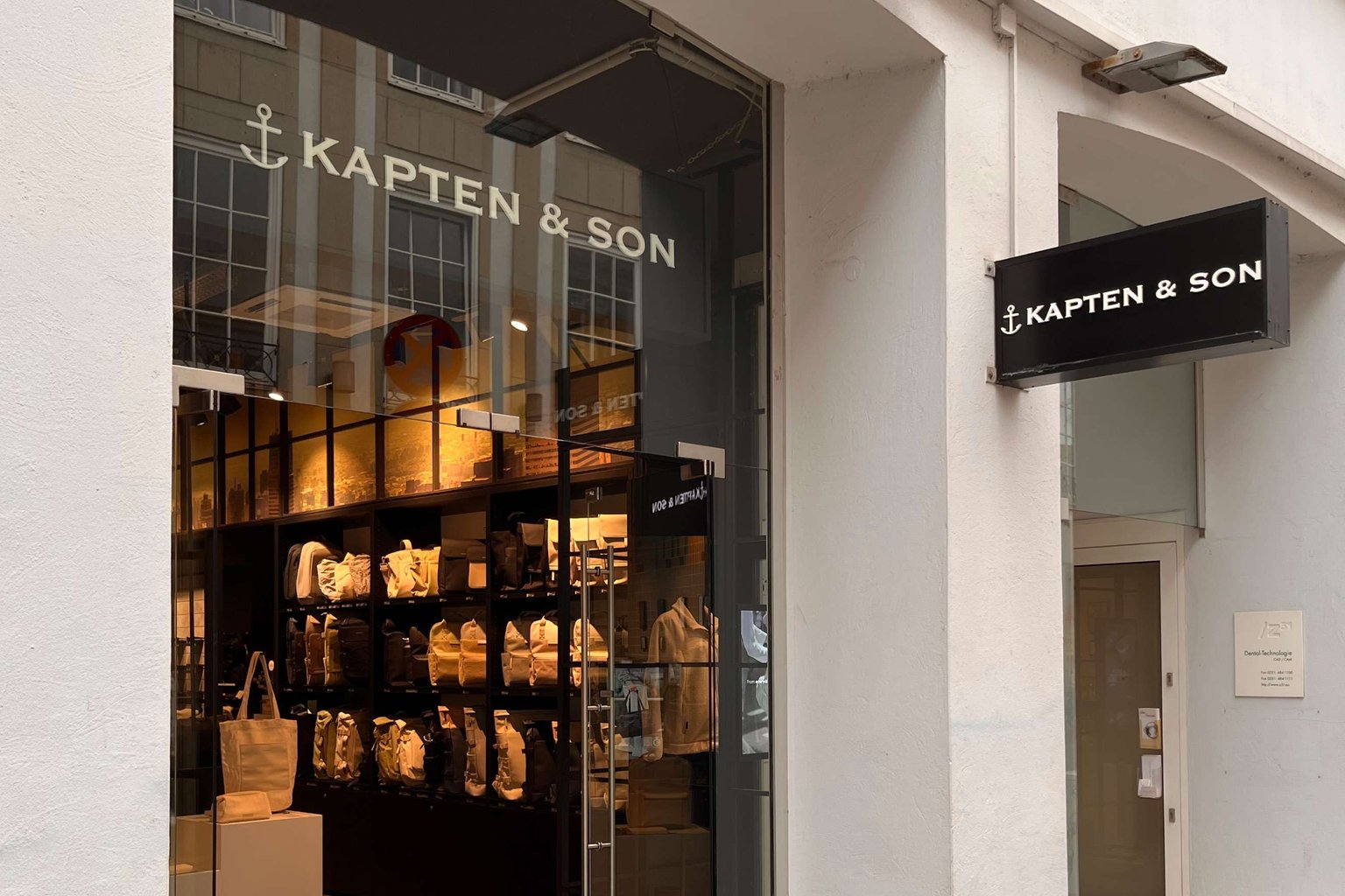 Außenansicht eines Kapten & Son Stores mit großem Schaufenster und Blick ins Ladeninnere
