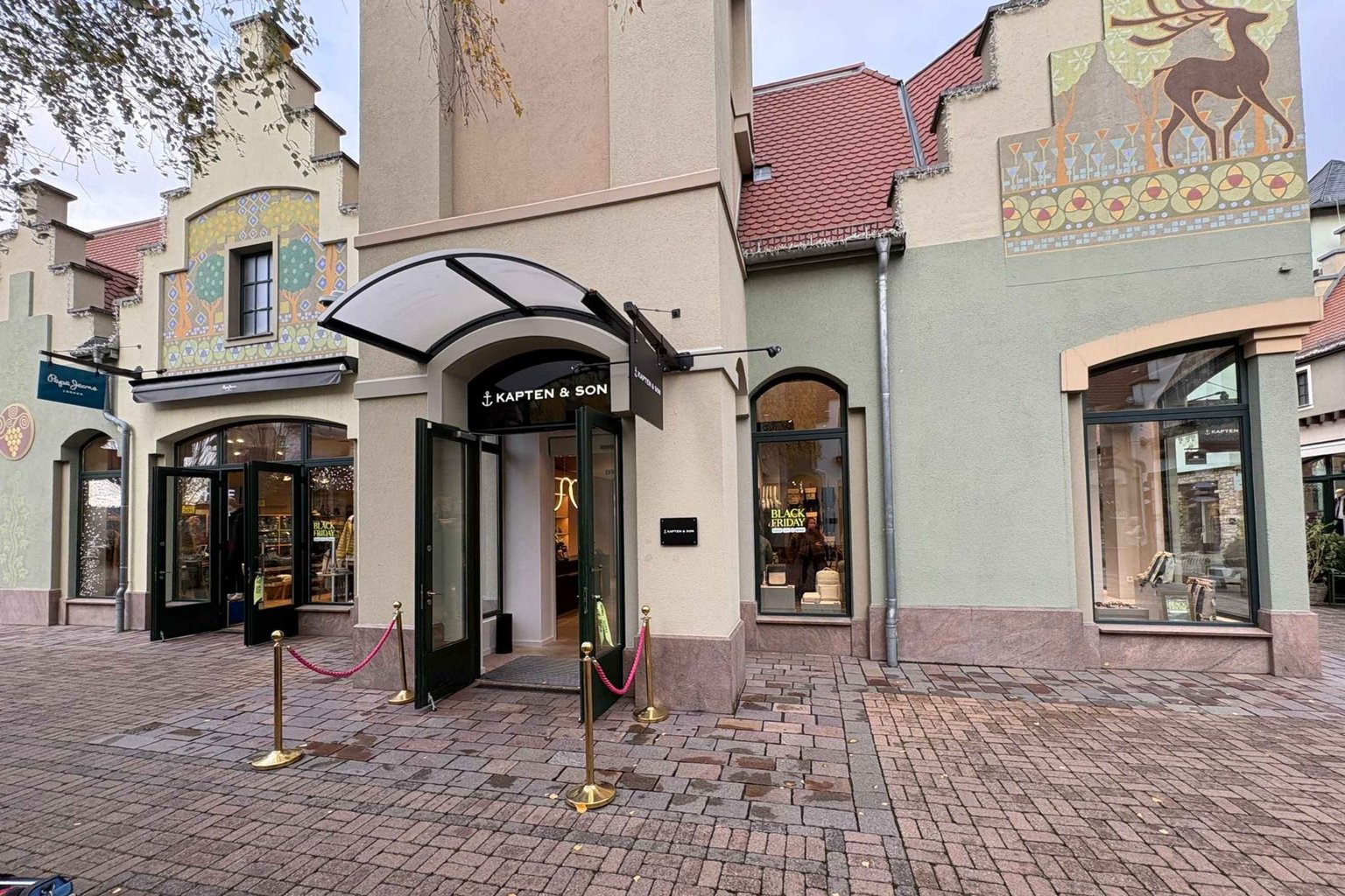 Außenansicht eines Kapten & Son Stores mit großem Schaufenster und Blick ins Ladeninnere
