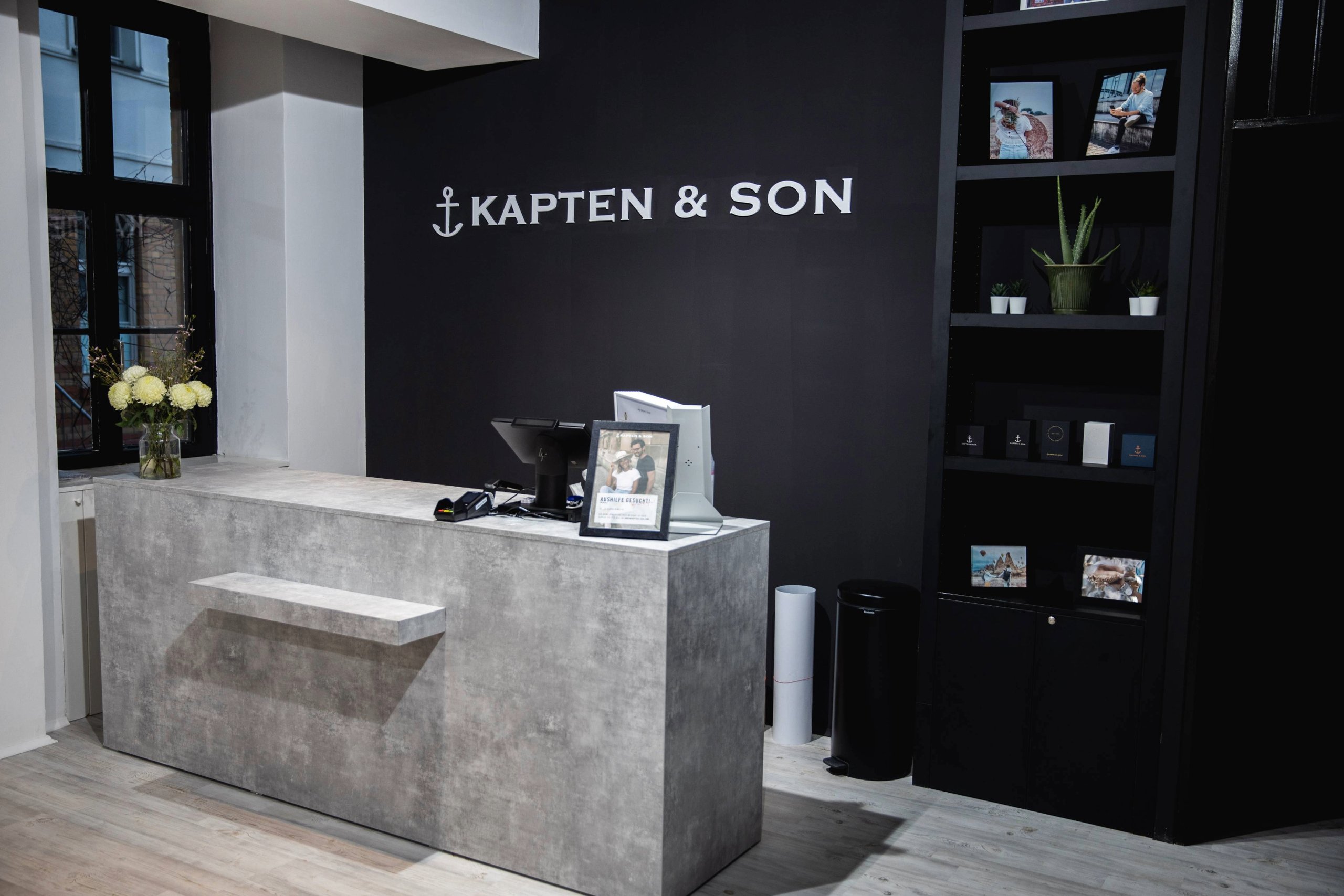 Kapten & Son Experience Store – Ladenfront mit beleuchtetem Logo, Rucksäcken, Taschen und Reisegepäck in den Schaufenstern