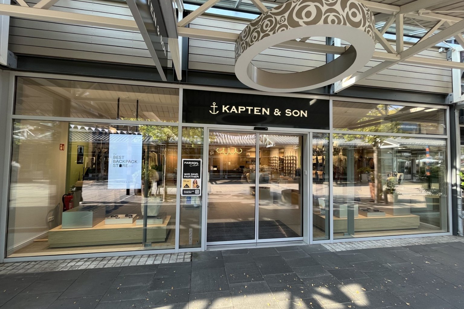 Außenansicht eines Kapten & Son Stores mit großem Schaufenster und Blick ins Ladeninnere