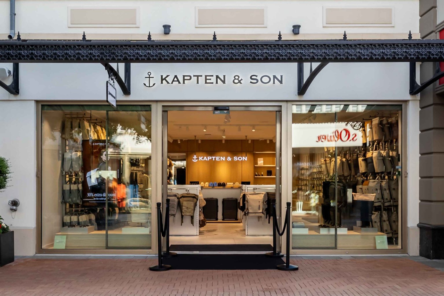 Außenansicht eines Kapten & Son Stores mit großem Schaufenster und Blick ins Ladeninnere