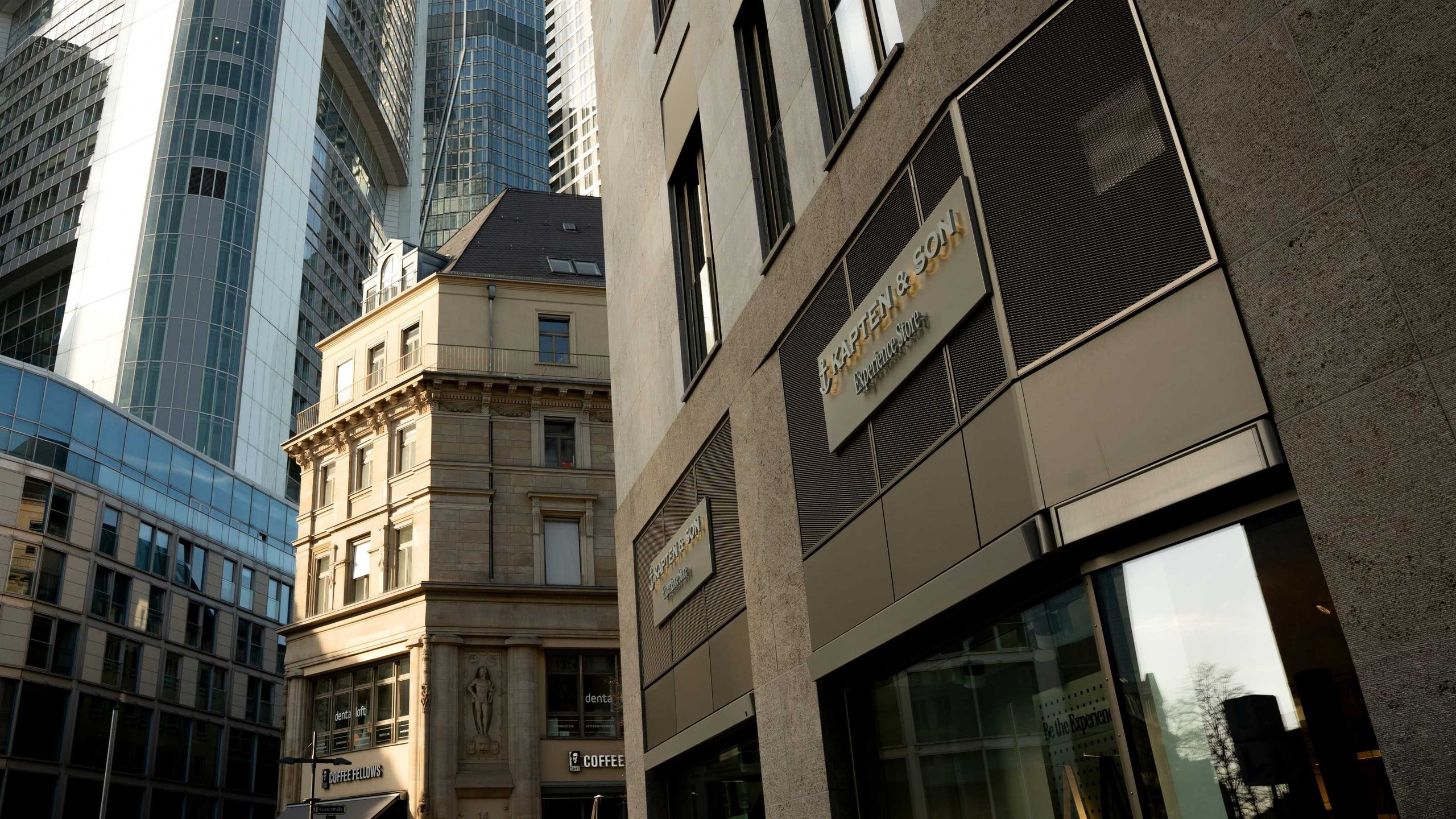 Kapten & Son Experience Store – Ladenfront mit beleuchtetem Logo, Rucksäcken, Taschen und Reisegepäck in den Schaufenstern