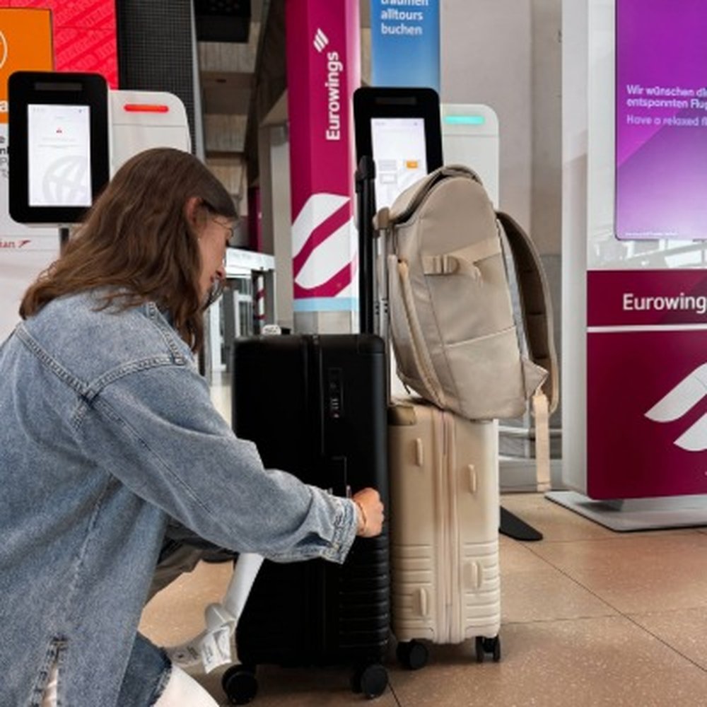 frau prüft koffer und handgepäck-rucksack vor check in schalter