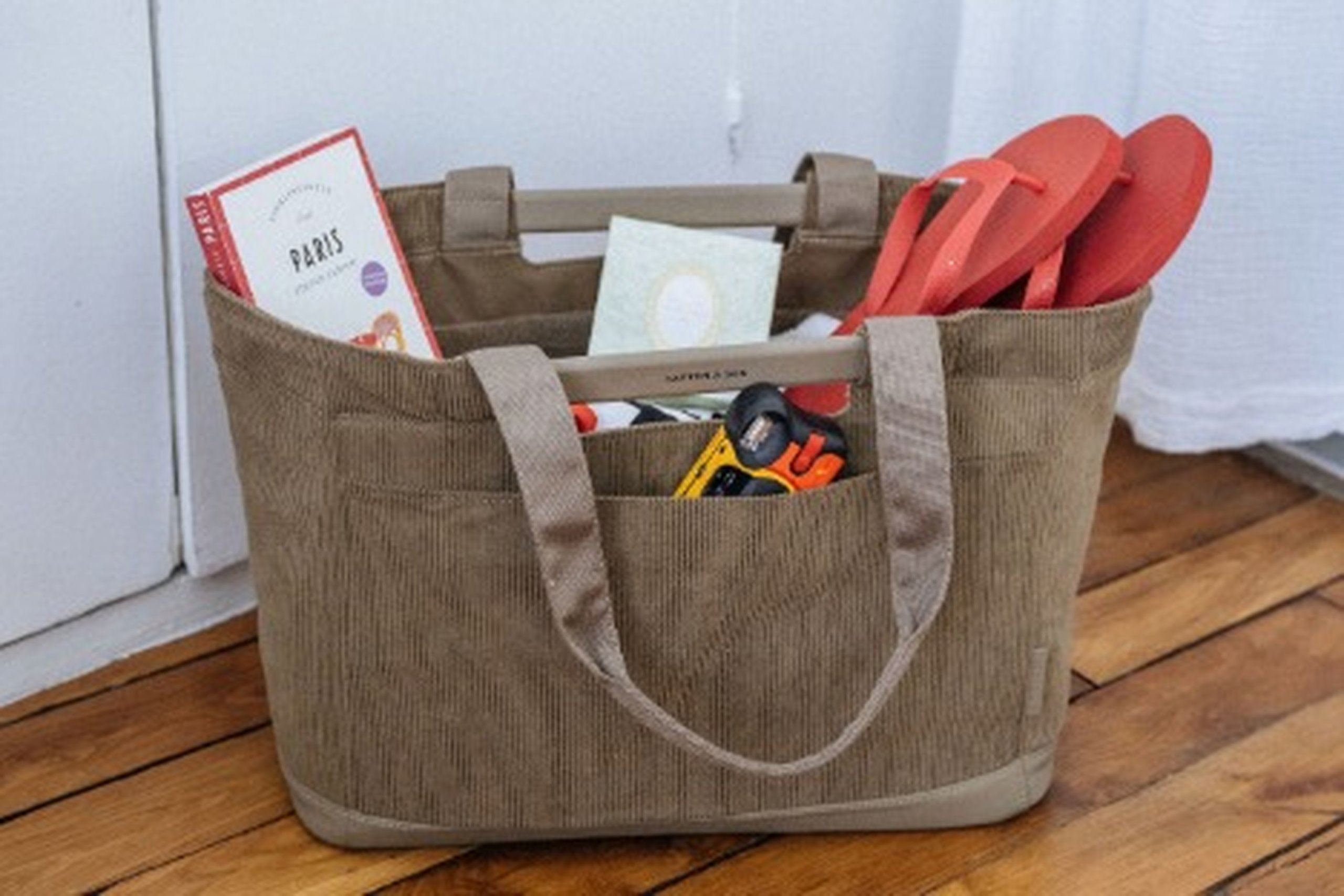 Cesta de compra convertida en bolsa de playa, con chanclas, un libro y una cámara en su interior