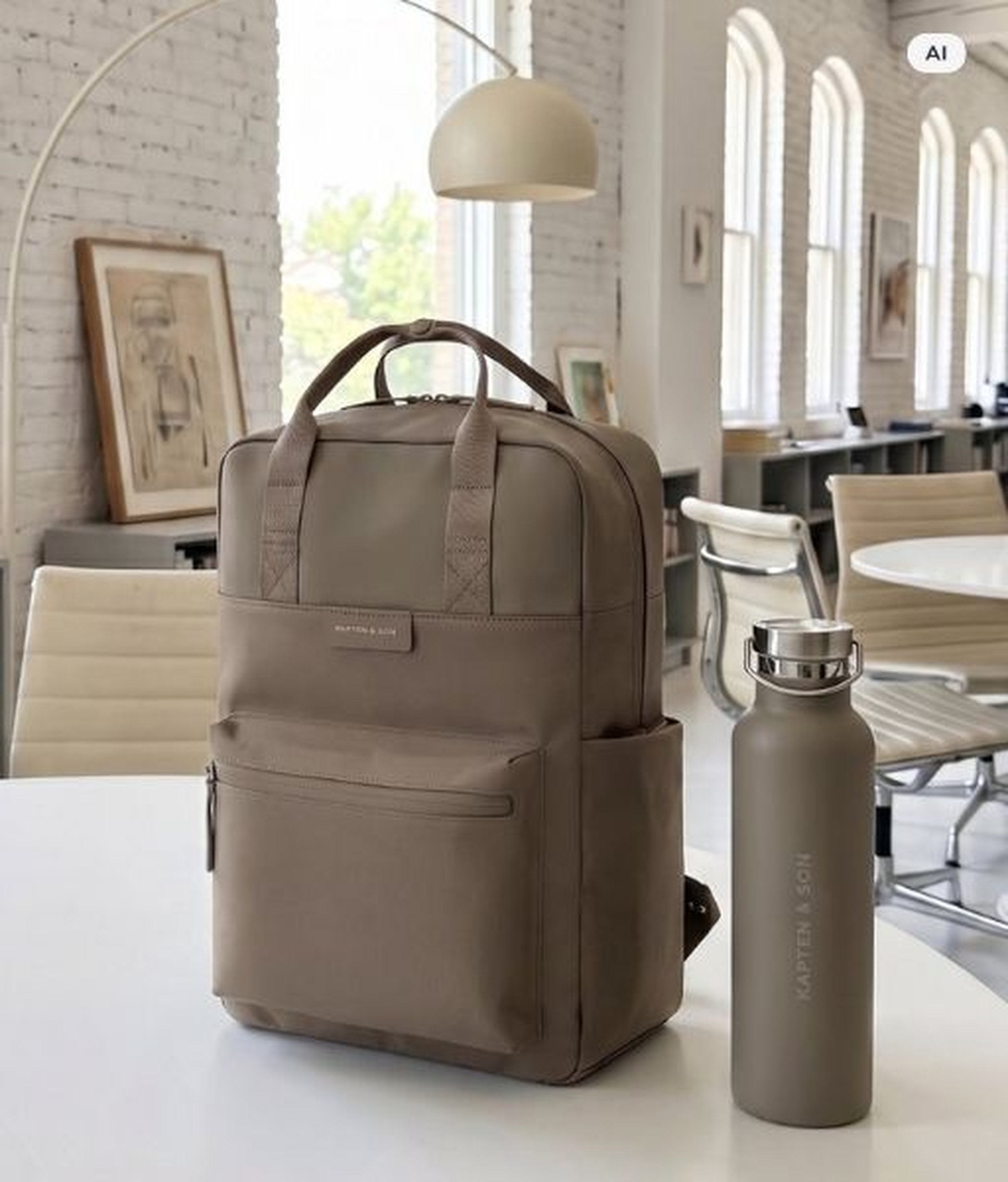 AI Generated Image: Een taupe Kapten & Son rugzak en een bijpassende Kapten & Son drinkfles op een witte tafel in een licht, modern kantoor.
