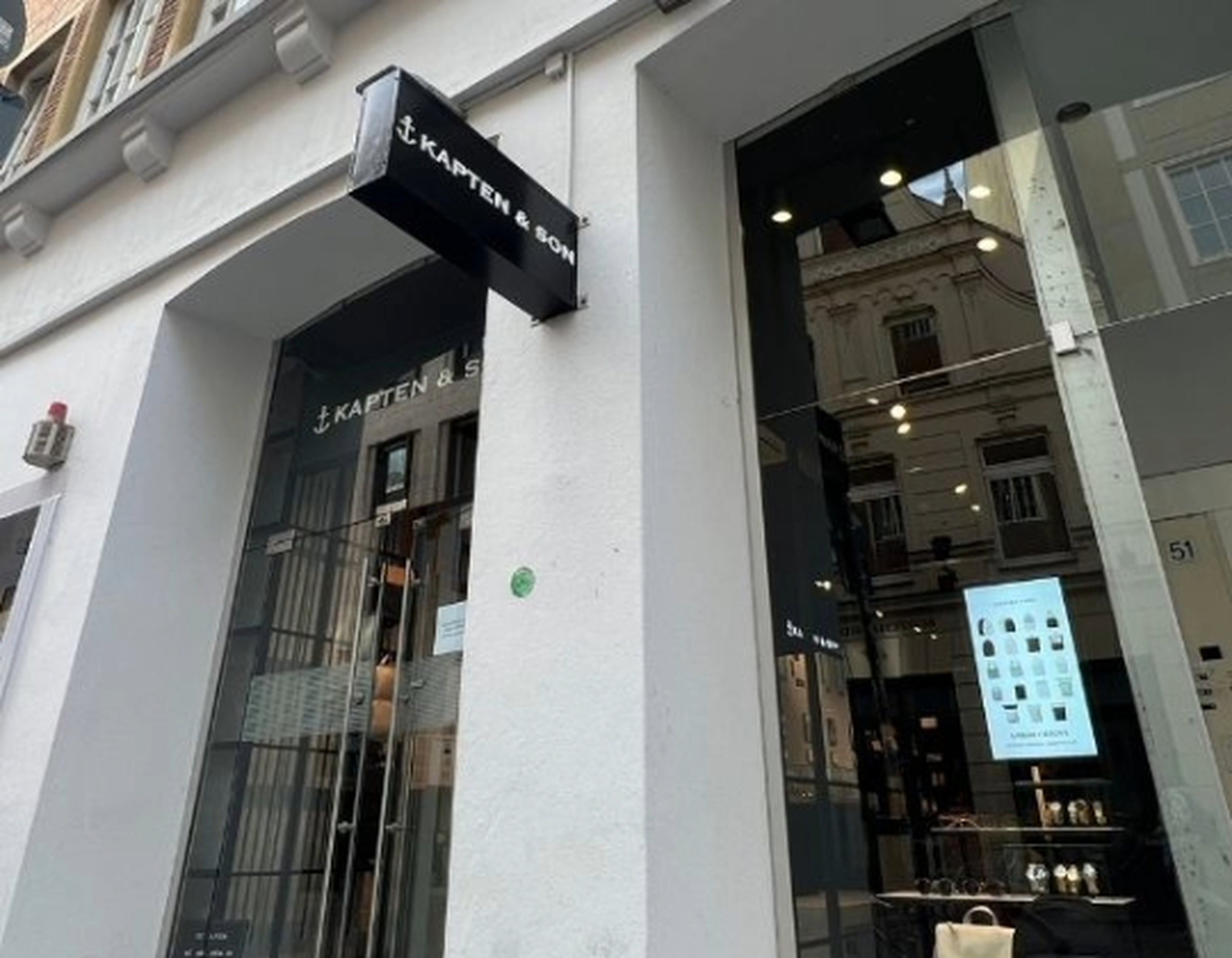 Kapten & Son Experience Store – Ladenfront mit beleuchtetem Logo, Rucksäcken, Taschen und Reisegepäck in den Schaufenstern